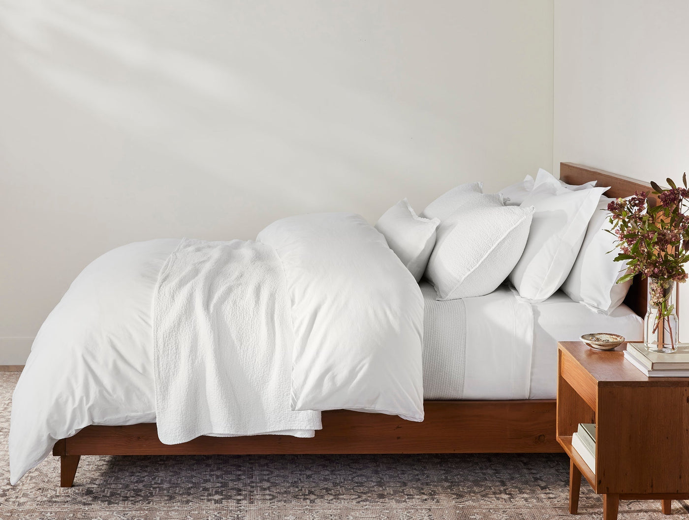 Coyuchi Heritage Percale sham in white, styled on a fully made bed with wood frame.