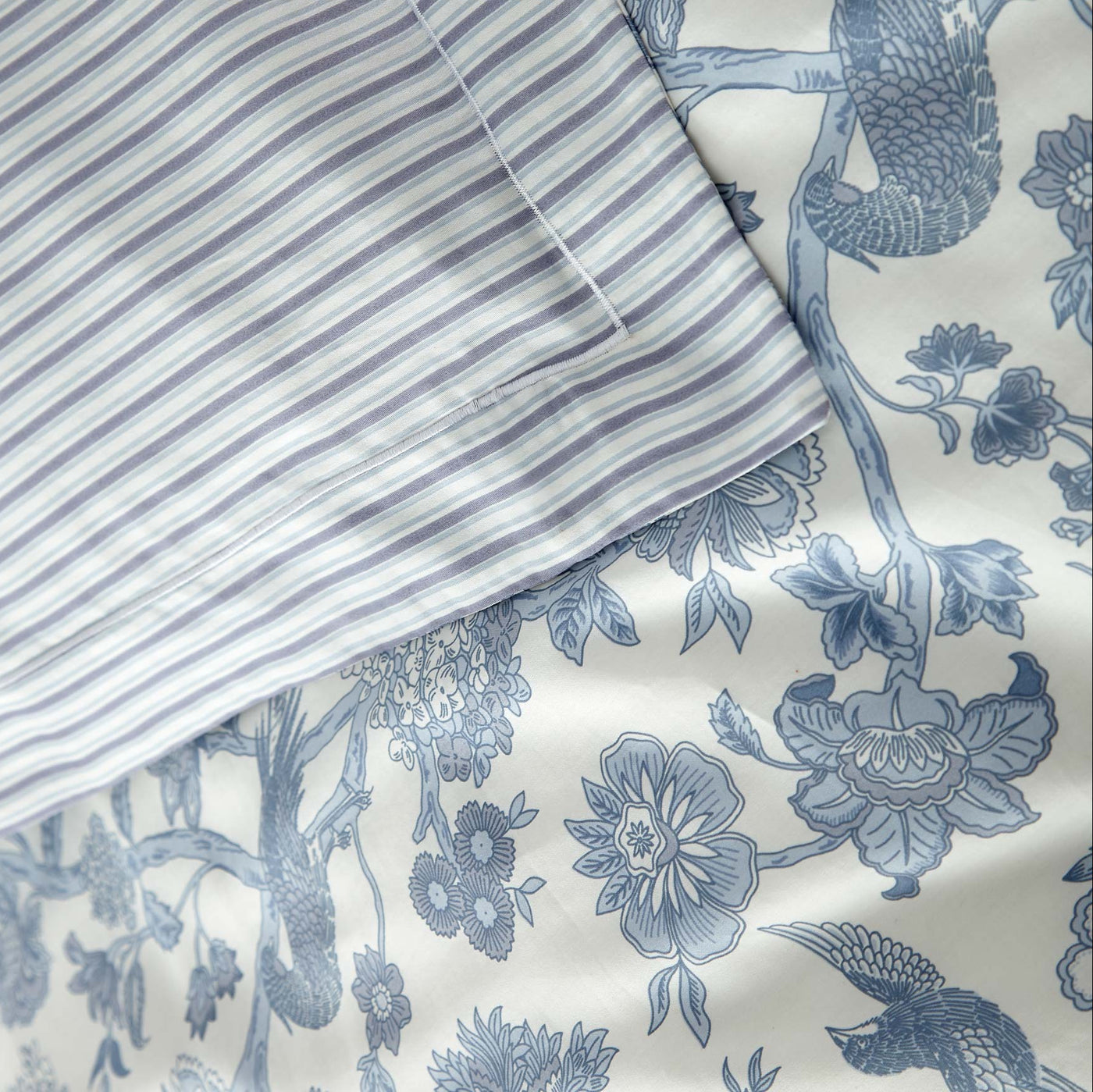 Floral and bird patterned fabric with a striped pillowcase.