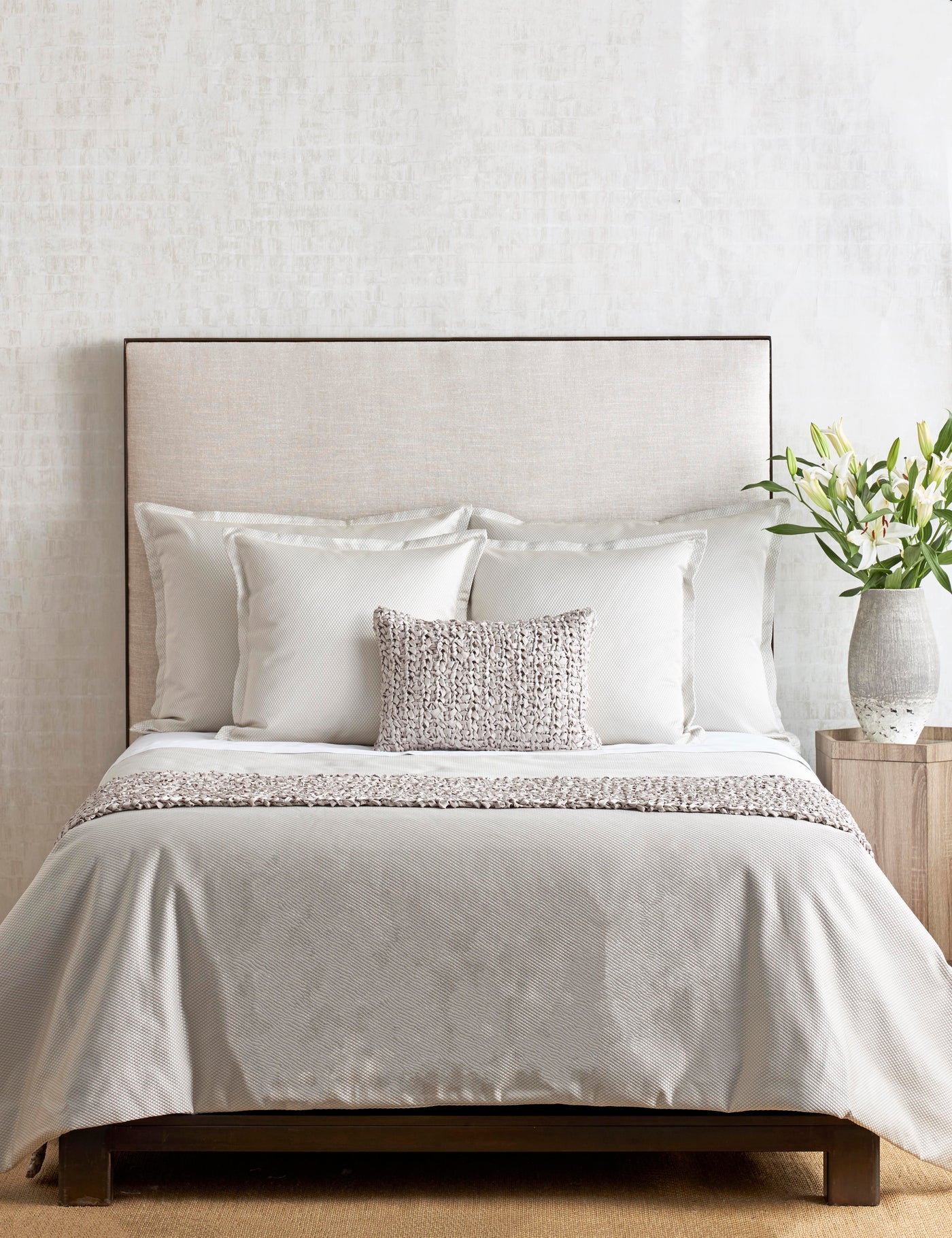 Ivory velvet coverlet draped on a styled bed with layered white pillows and a textured throw pillow.