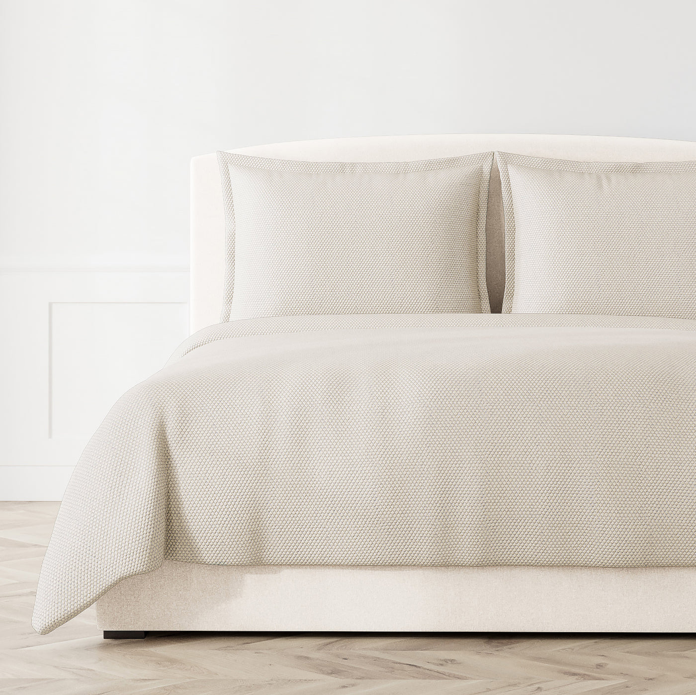 Ivory textured coverlet and shams styled on a bed, showing woven diamond pattern detail.