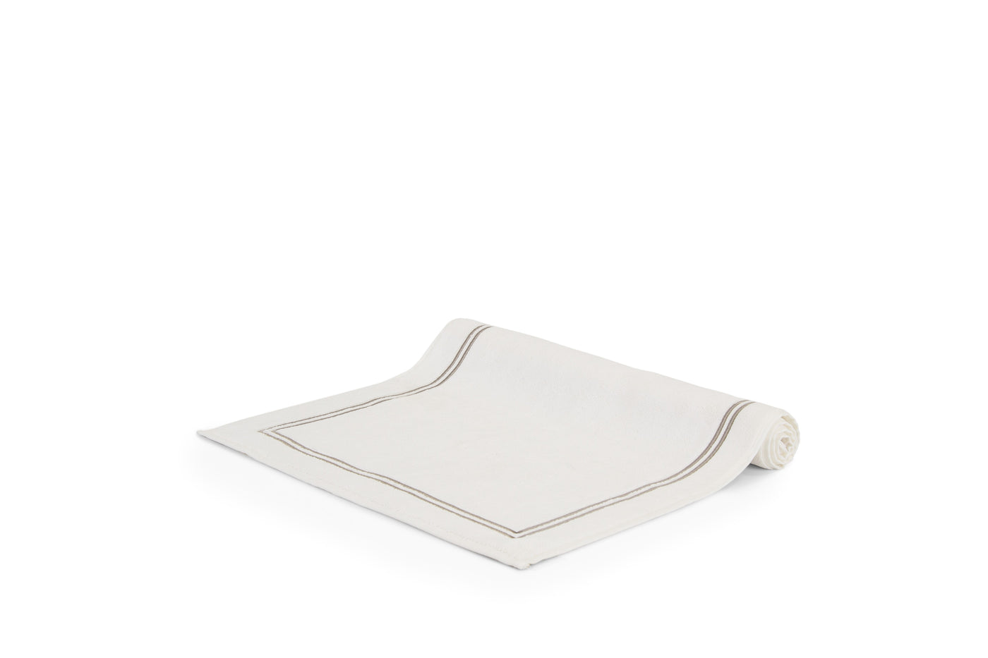 The Frette Classic | Bath Mat by Frette, featuring a simple border design and high absorbency, is displayed rolled on a white surface—ideal for any luxury bath collection.
