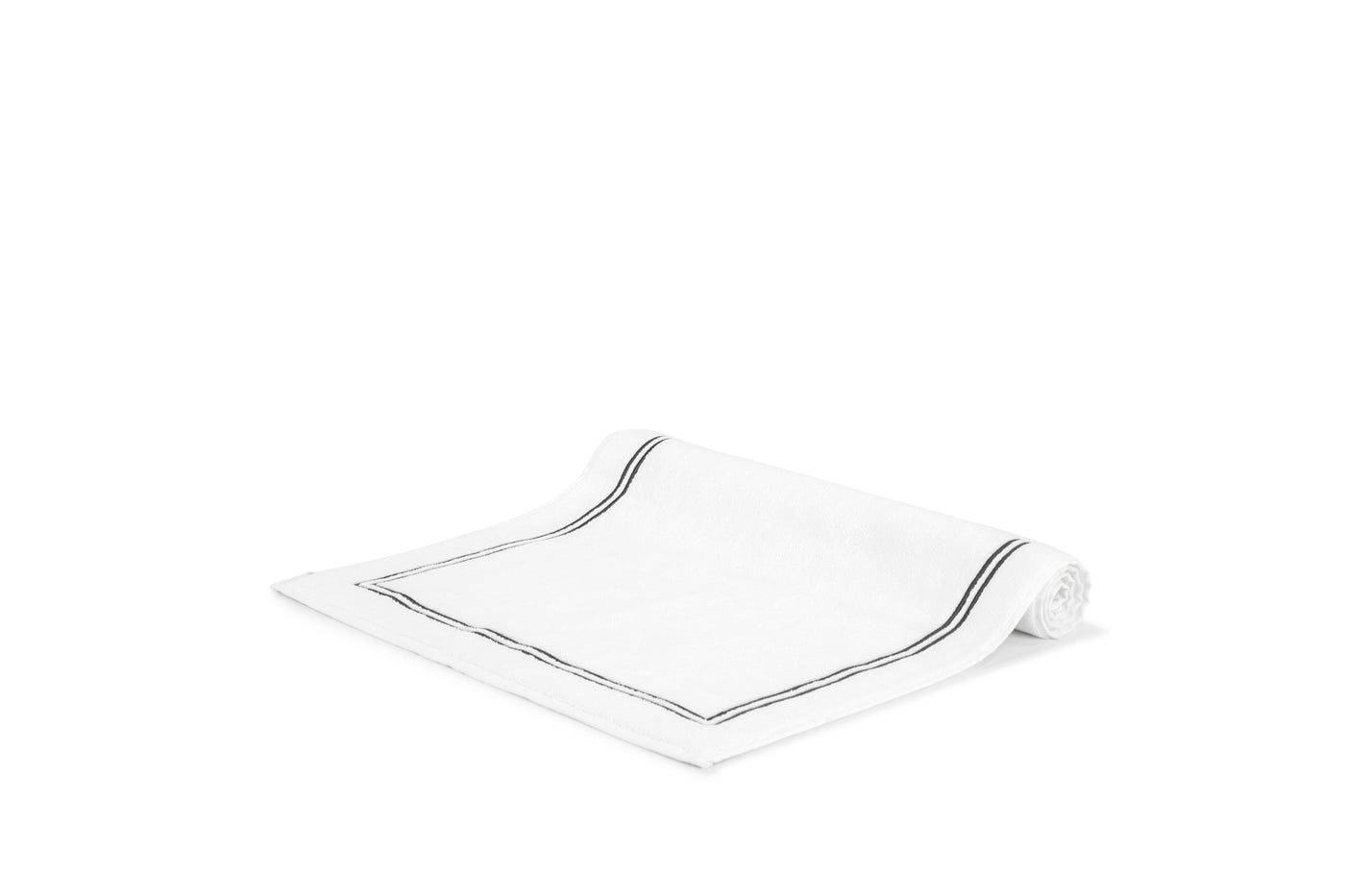 The Frette Classic Bath Mat by Frette features a highly absorbent, neatly rolled design with a single black border stripe, displayed on a plain white background.