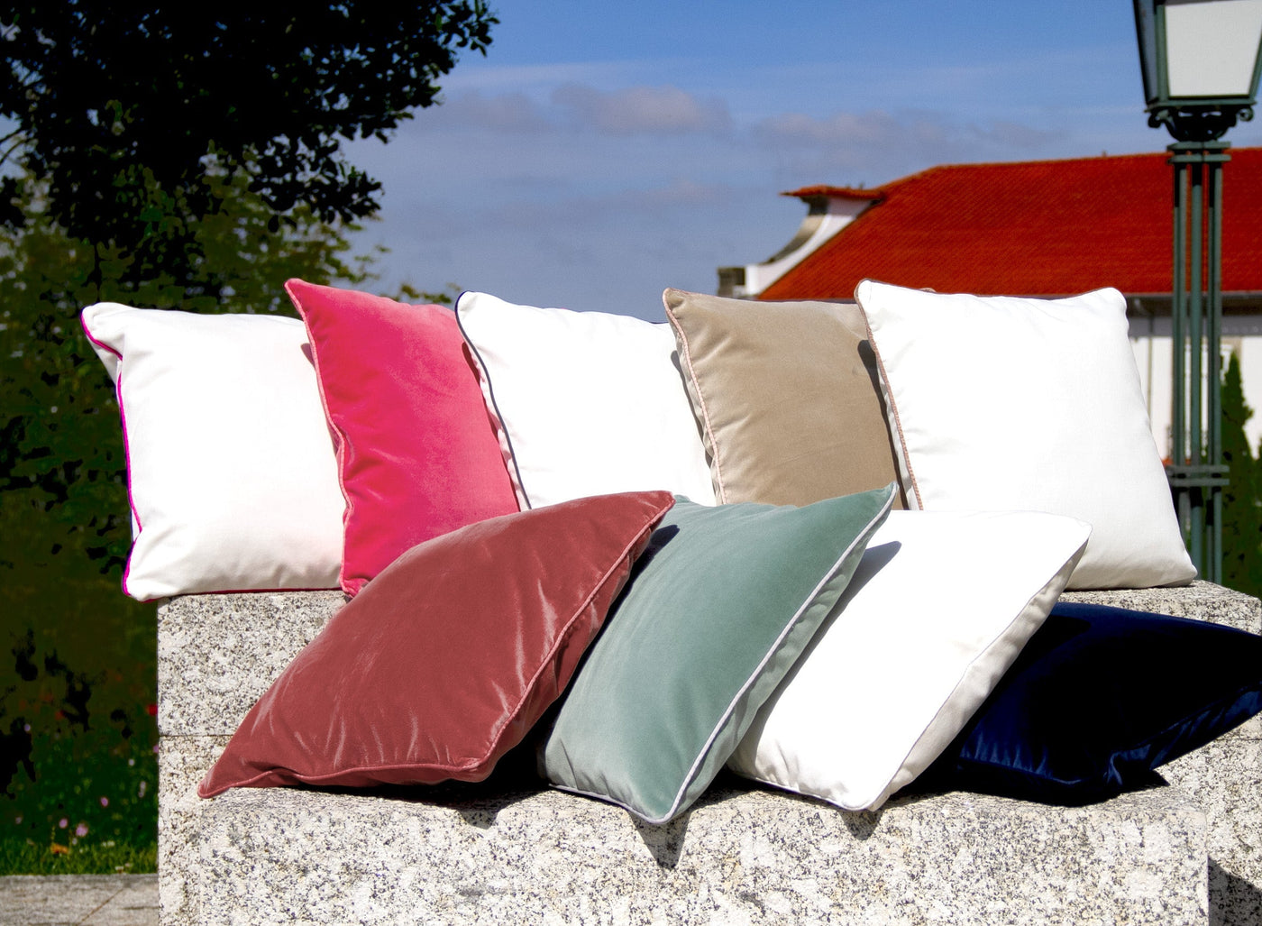 Colorful pillows on a stone wall with a garden background