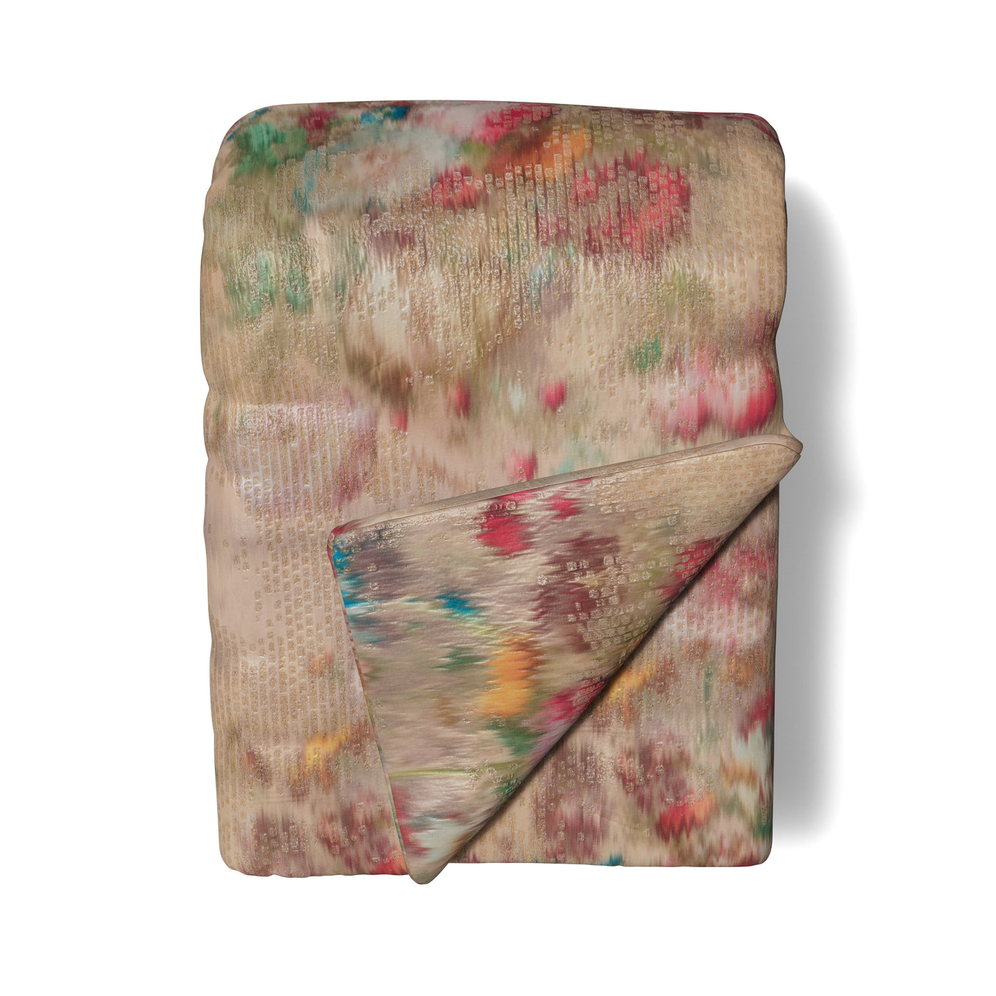 Ann Gish Ibiza throw folded, sand with blurred multicolor floral print, quilted texture visible.
