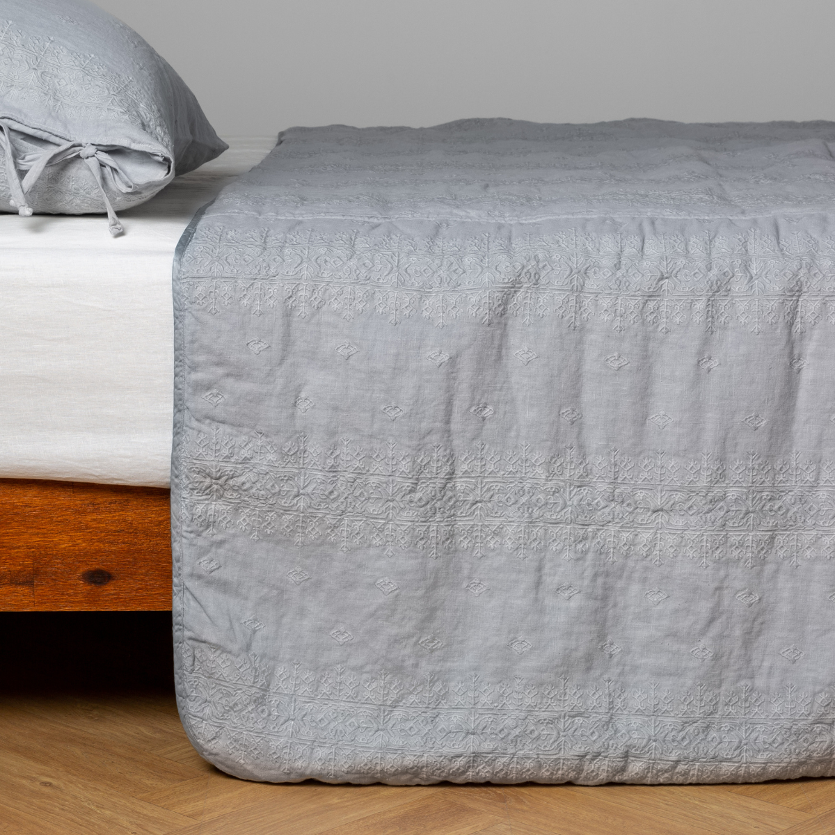 Bella Notte Ines bedspread in Cloud draped over foot of bed, showing quilted border detail.