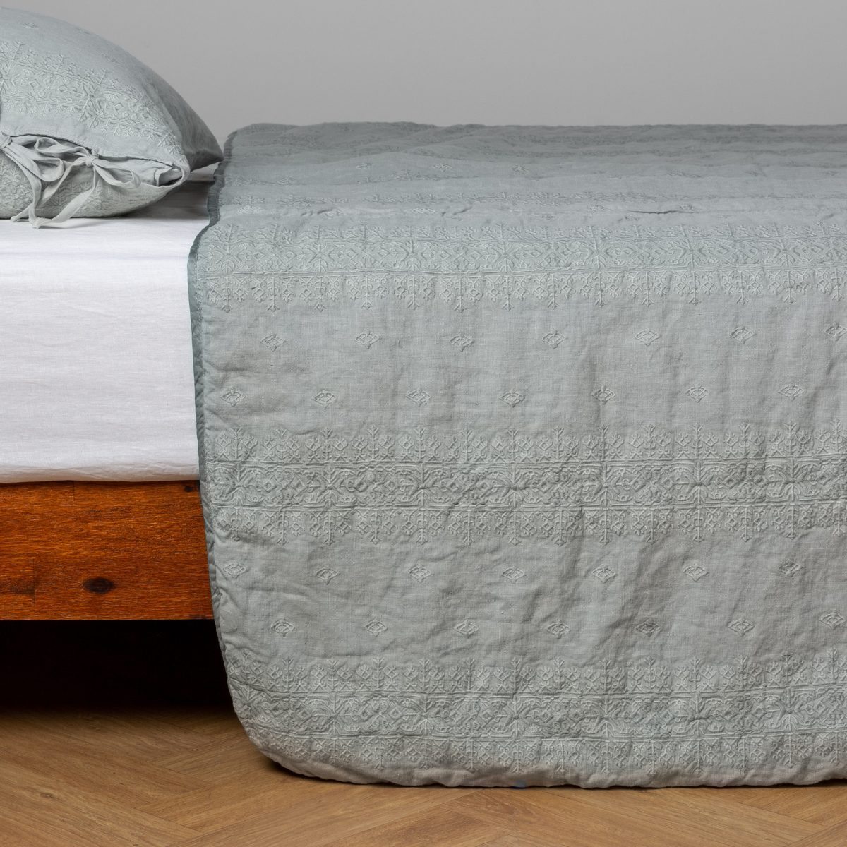 Eucalyptus bedspread draped over bed foot, showing quilted texture and matching pillow sham.