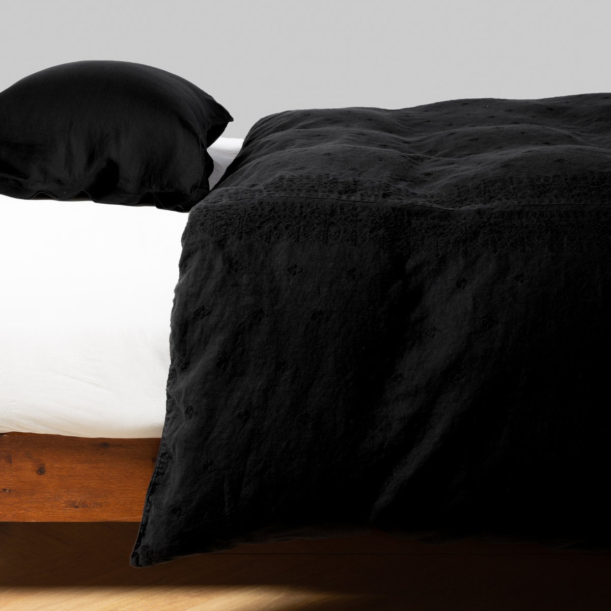 Bella Notte Ines duvet cover in Corvino, angled view showing textured black fabric draped over bed.