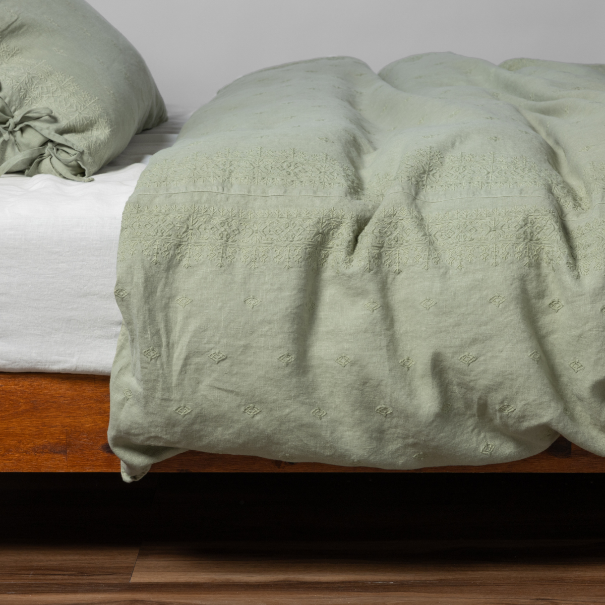Desert Sage Ines duvet cover draped loosely over a low wood platform bed.