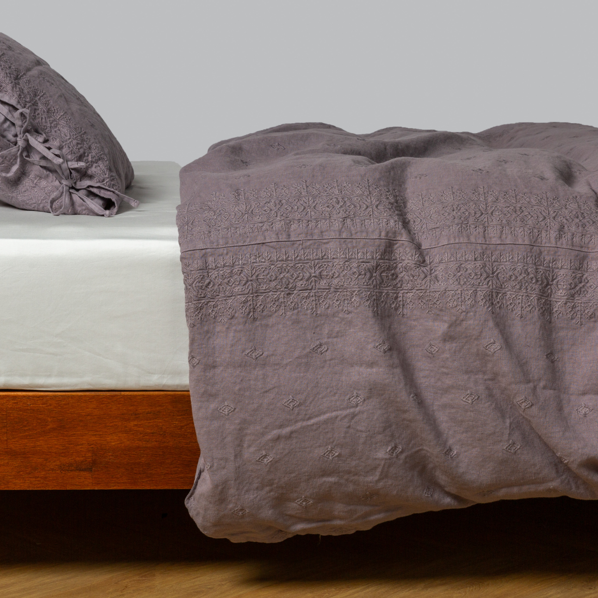 Bella Notte Ines duvet cover in French Lavender, draped over bed showing textured lace trim detail.