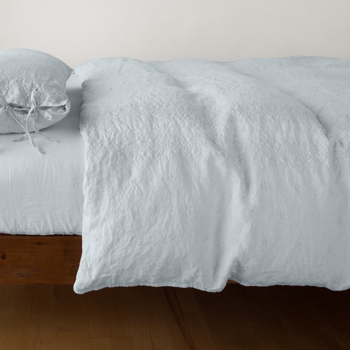 Bella Notte Ines duvet cover in Cloud, shown draped over bed with relaxed linen texture.