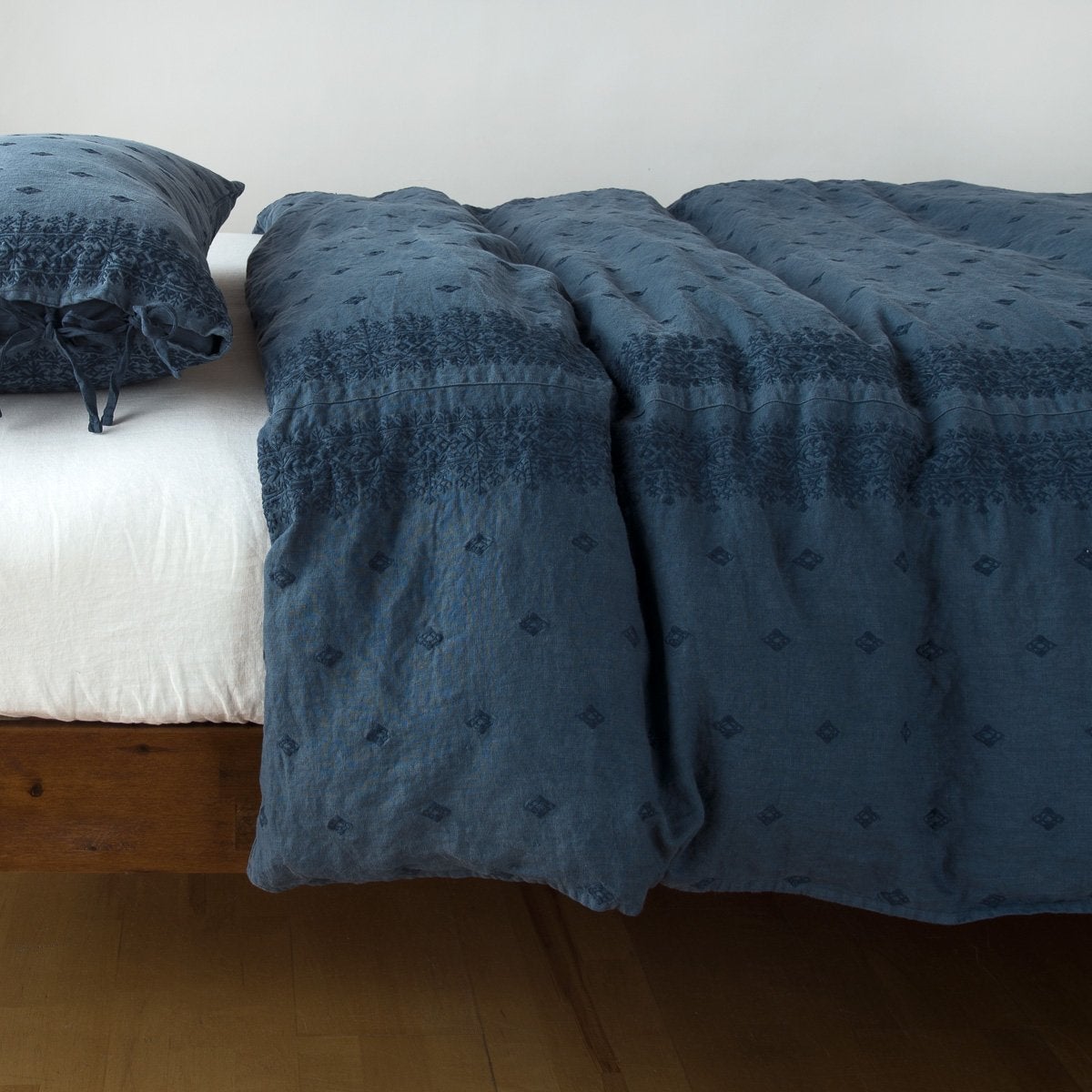 Midnight Bella Notte Ines duvet cover draped over bed, showing tonal embroidered pattern detail.