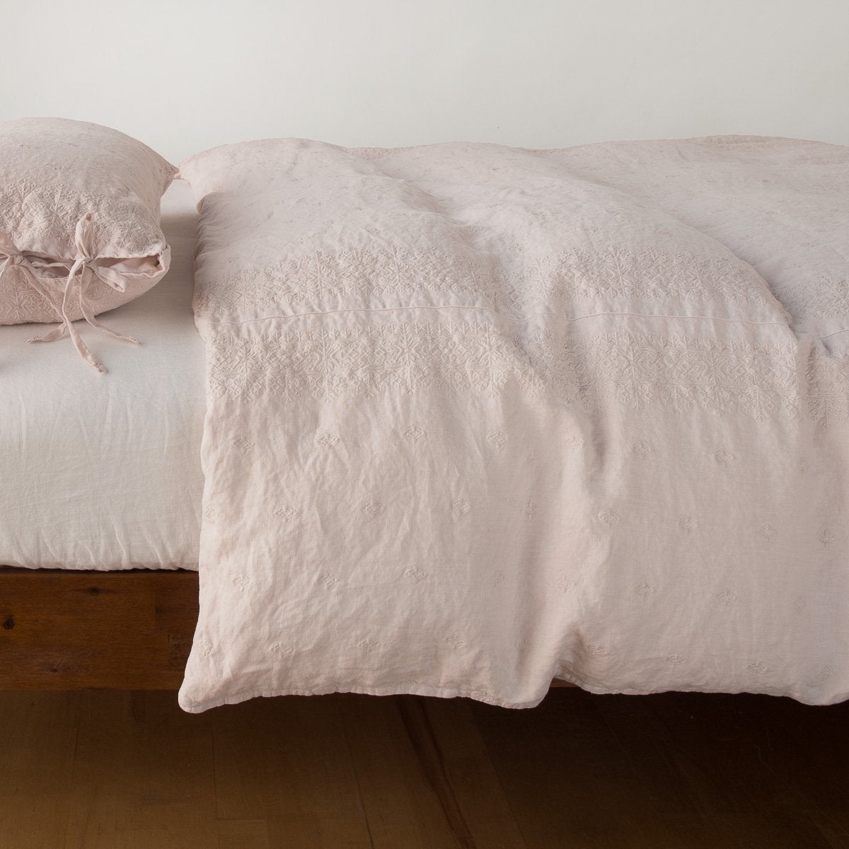 Bella Notte Ines duvet cover in Pearl, relaxed linen draping over a styled bed with tie-closure pillow.