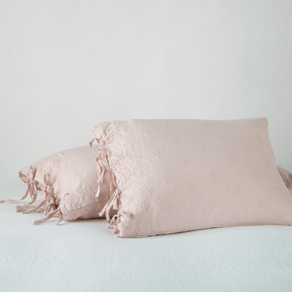 Bella Notte Ines shams in Pearl linen with tied ribbon closures, styled on a bed.
