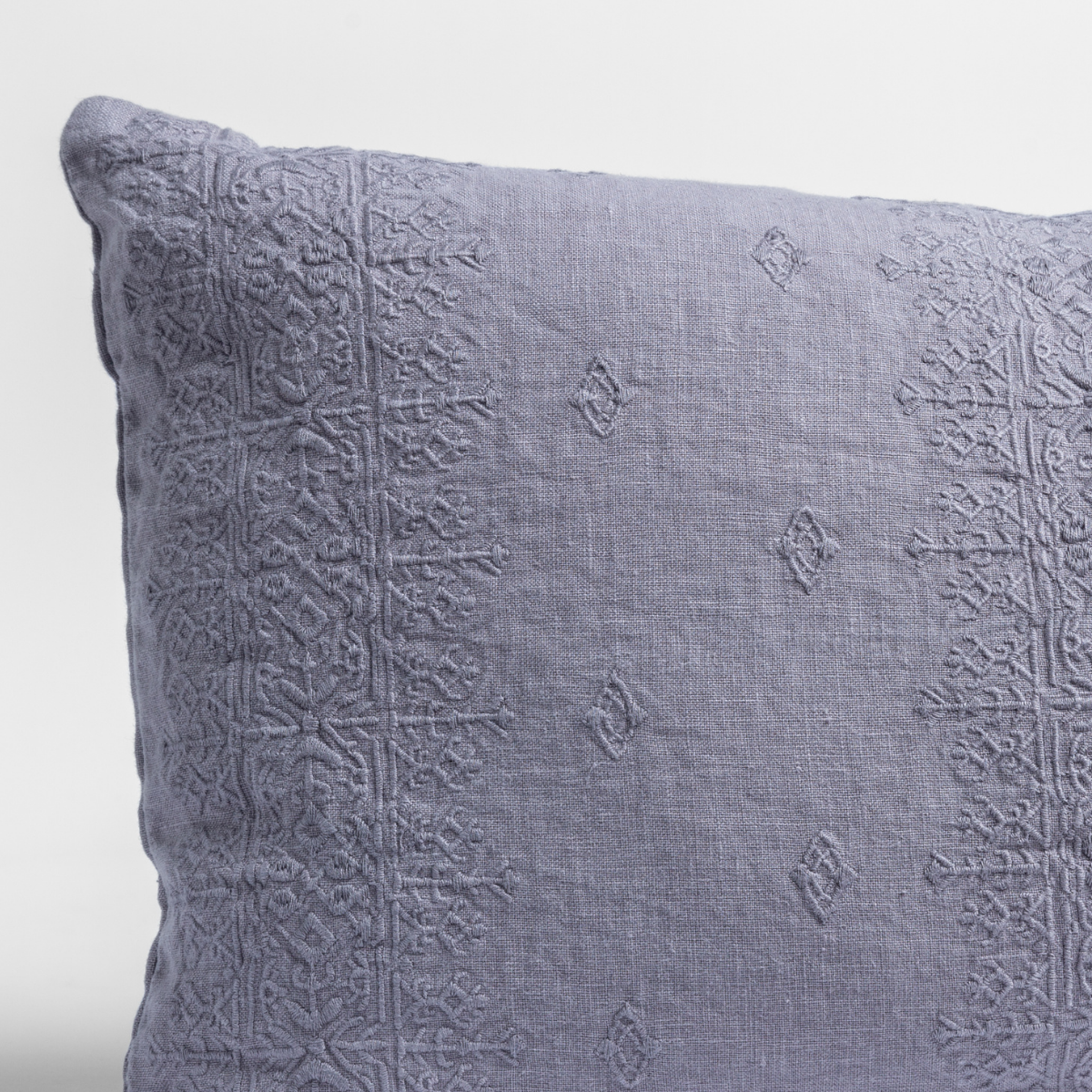 Close-up of French Lavender Ines sham corner showing tonal embroidered medallion pattern on linen.
