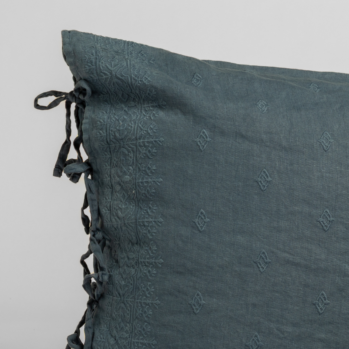 Close-up of Midnight Ines sham corner showing embossed pattern and tassel trim detail.