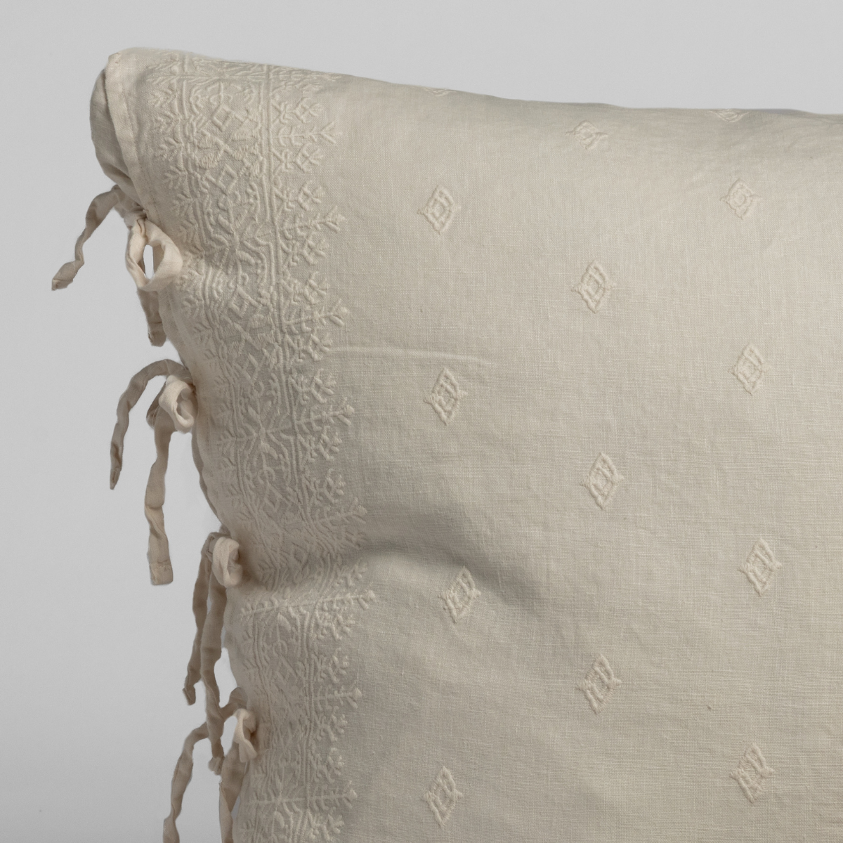 Close-up of Bella Notte Ines sham in Natural, showing embroidered diamond motifs and tassel ties.