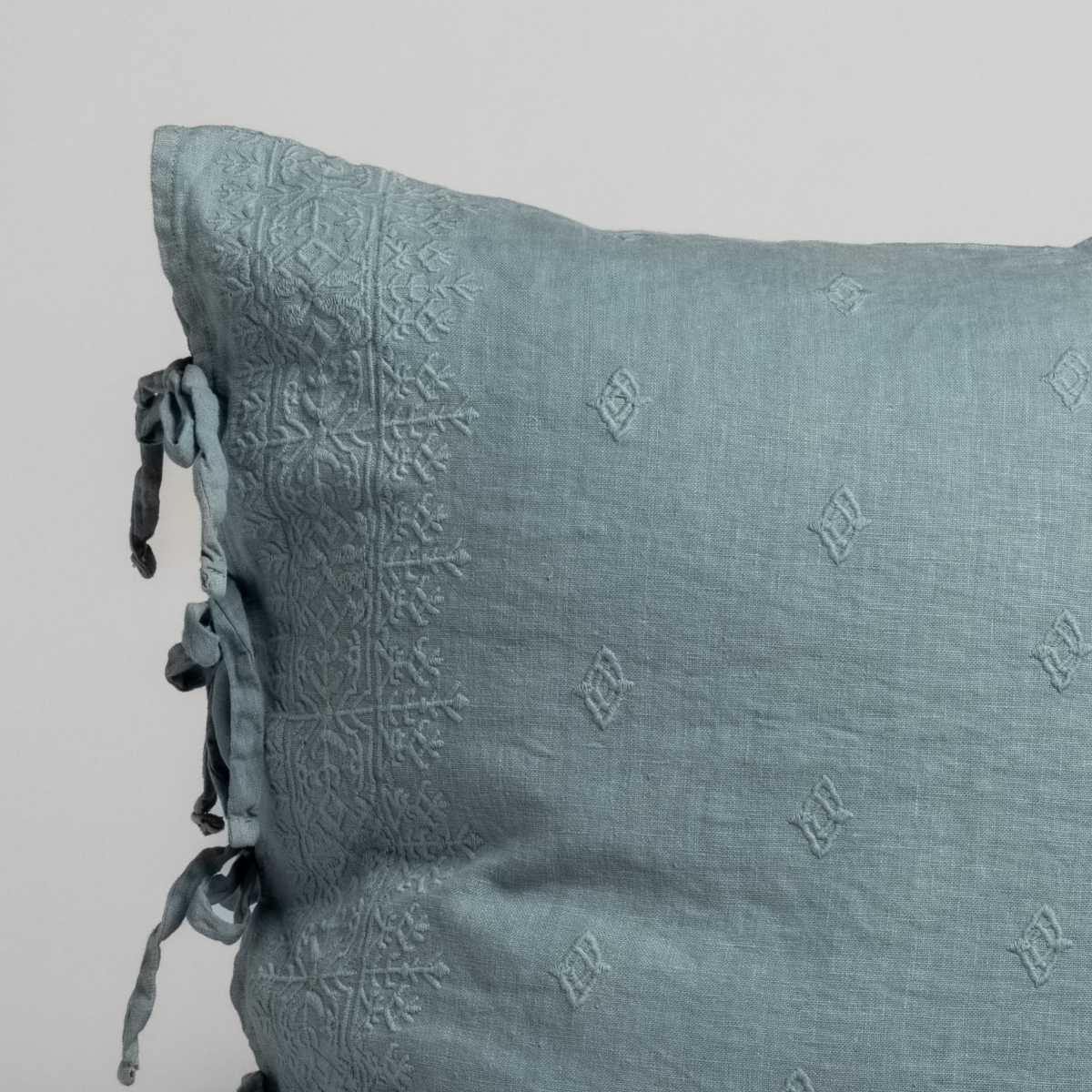 Close-up of Tahoe Blue linen sham corner with embossed medallion pattern and ribbon ties.