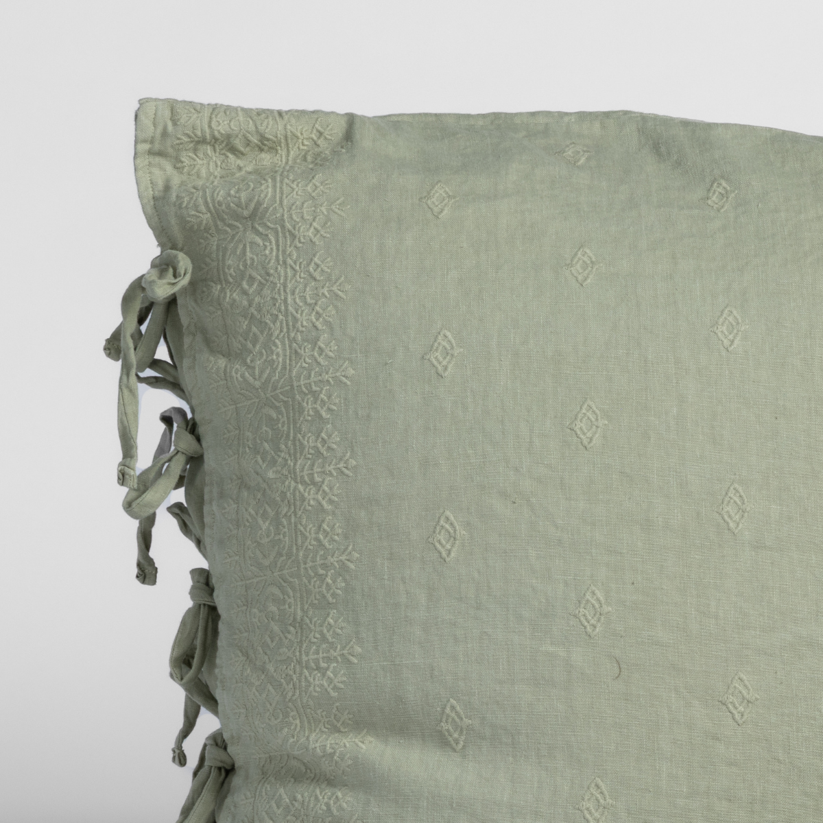 Close-up of Desert Sage sham corner with tonal embroidery and knotted tassel ties.