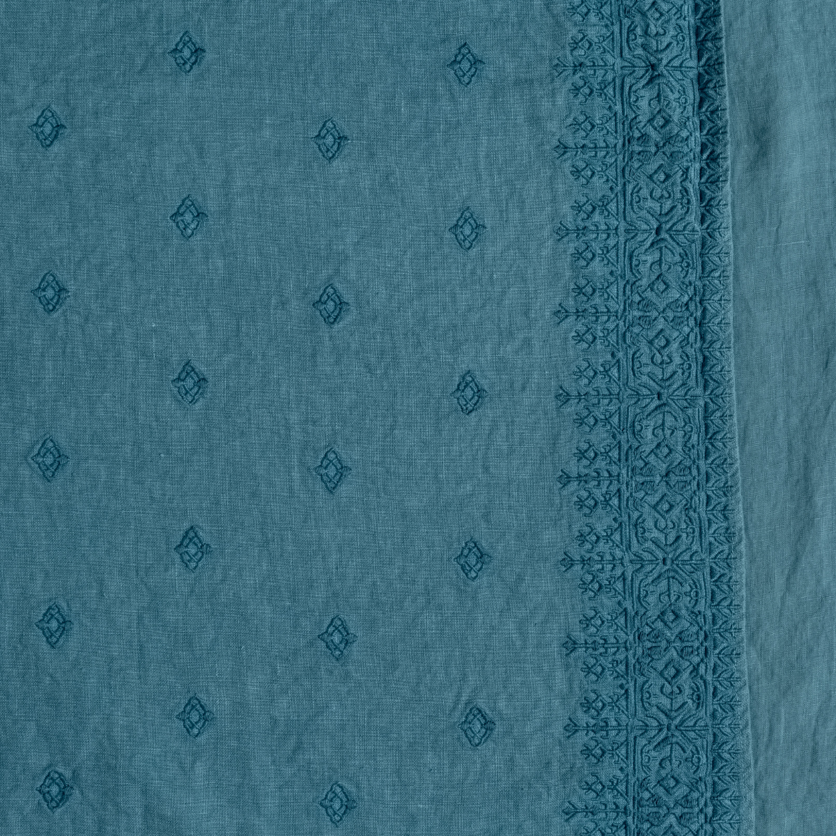 Close-up of Cenote linen with diamond embroidery and detailed border trim.