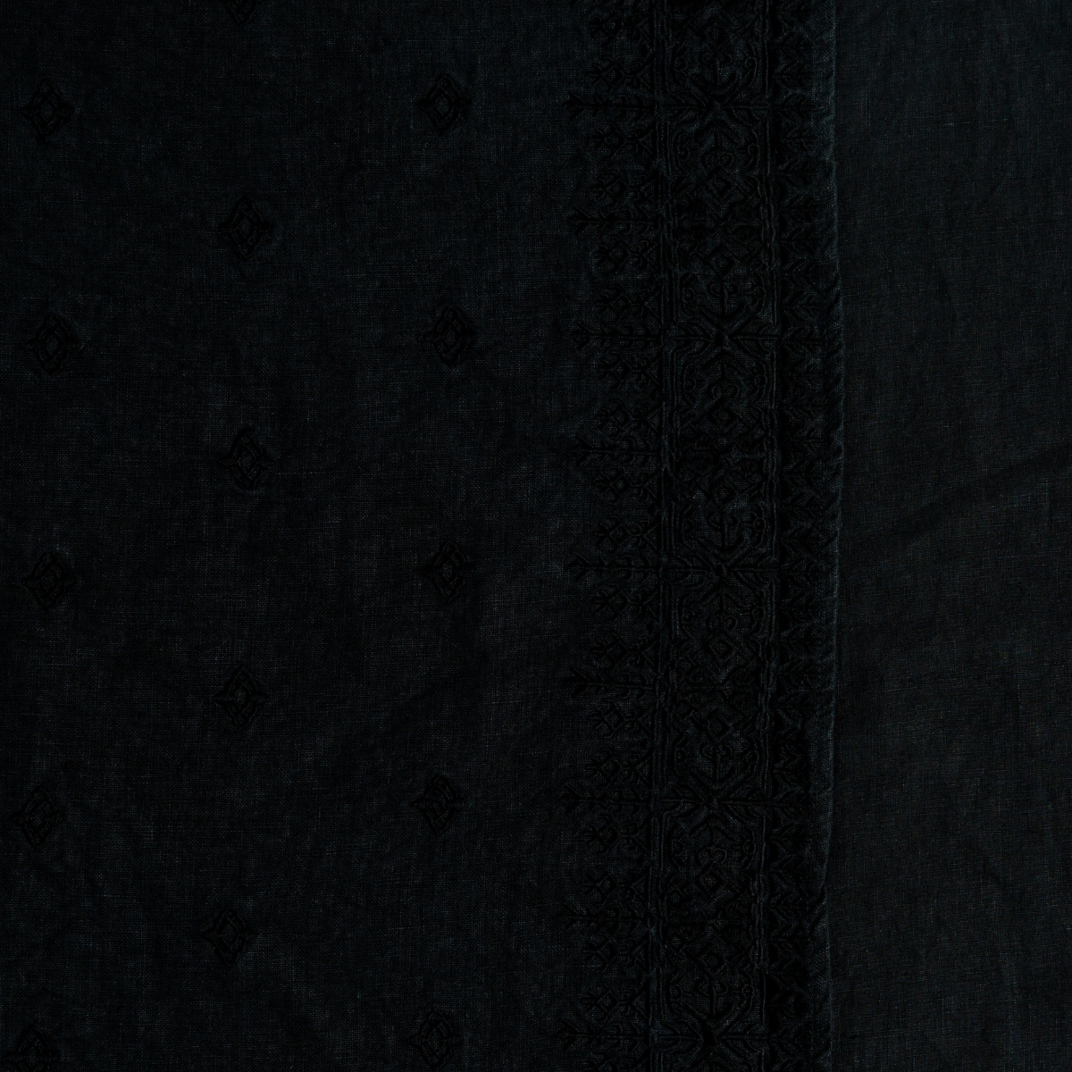 Close-up of Corvino Ines duvet cover hem, showing tonal embroidered border and dot pattern on black linen.