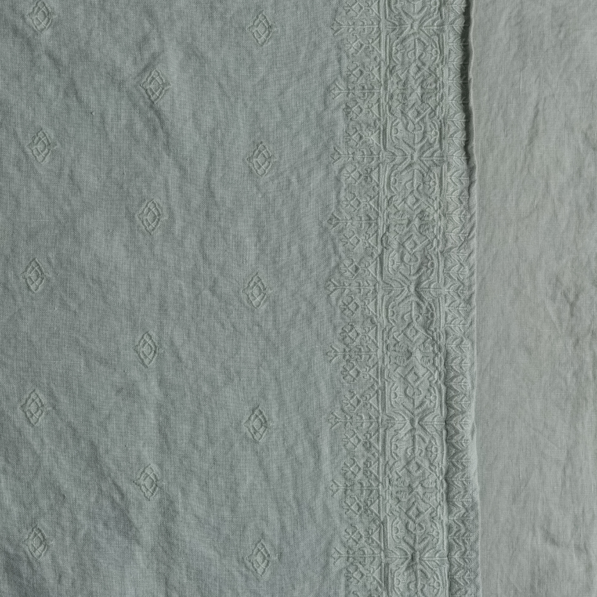 Close-up of Eucalyptus Ines duvet cover showing diamond motifs and ornate embroidered border trim.