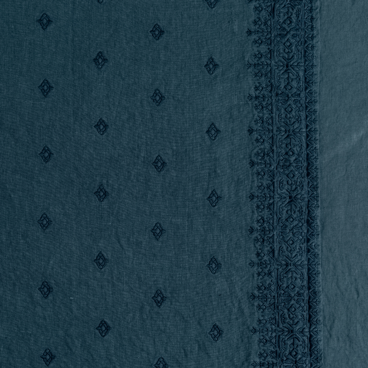 Close-up of Midnight linen sham with diamond motif field and ornate embroidered border trim.