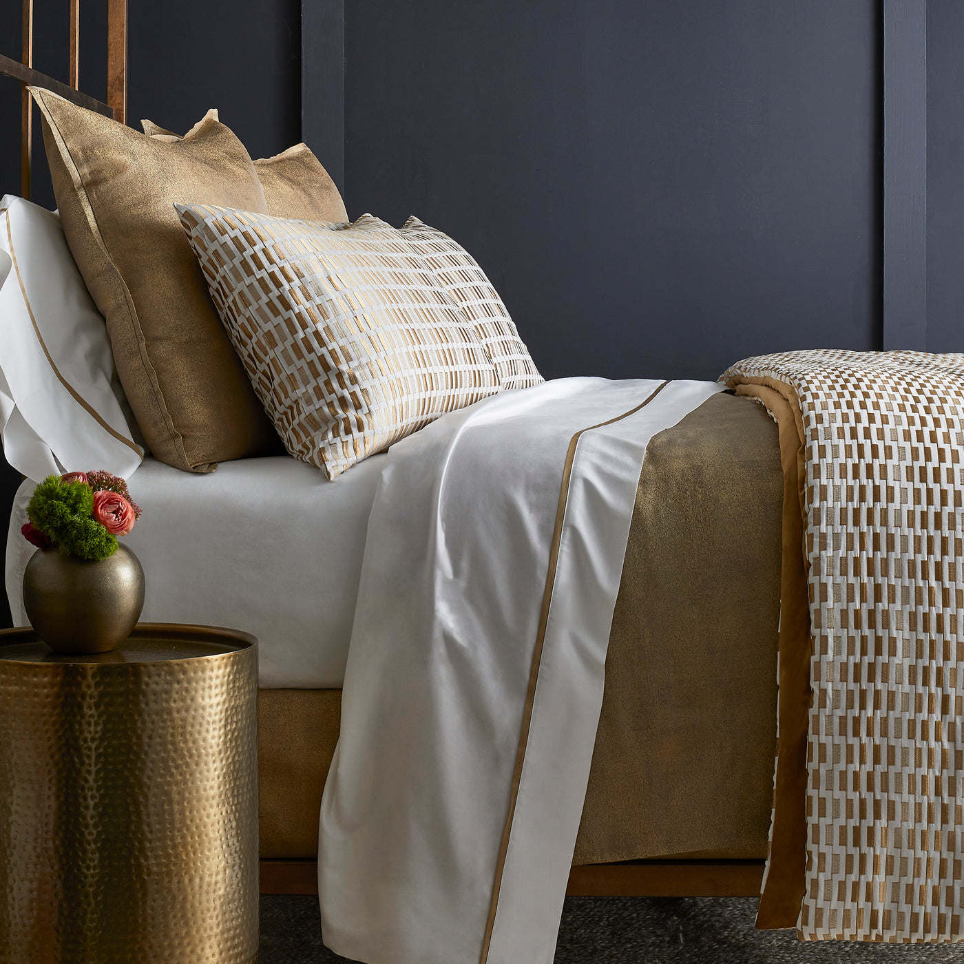 Close-up of Ann Gish Ingot sham in gold geometric grid pattern against white bedding.