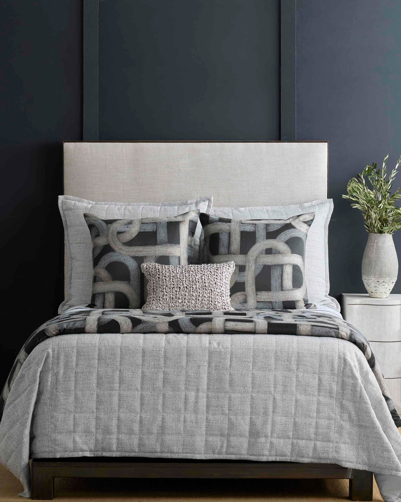 Charcoal and ivory geometric loop pattern on an Ann Gish Interchange pillow, styled on a made bed.