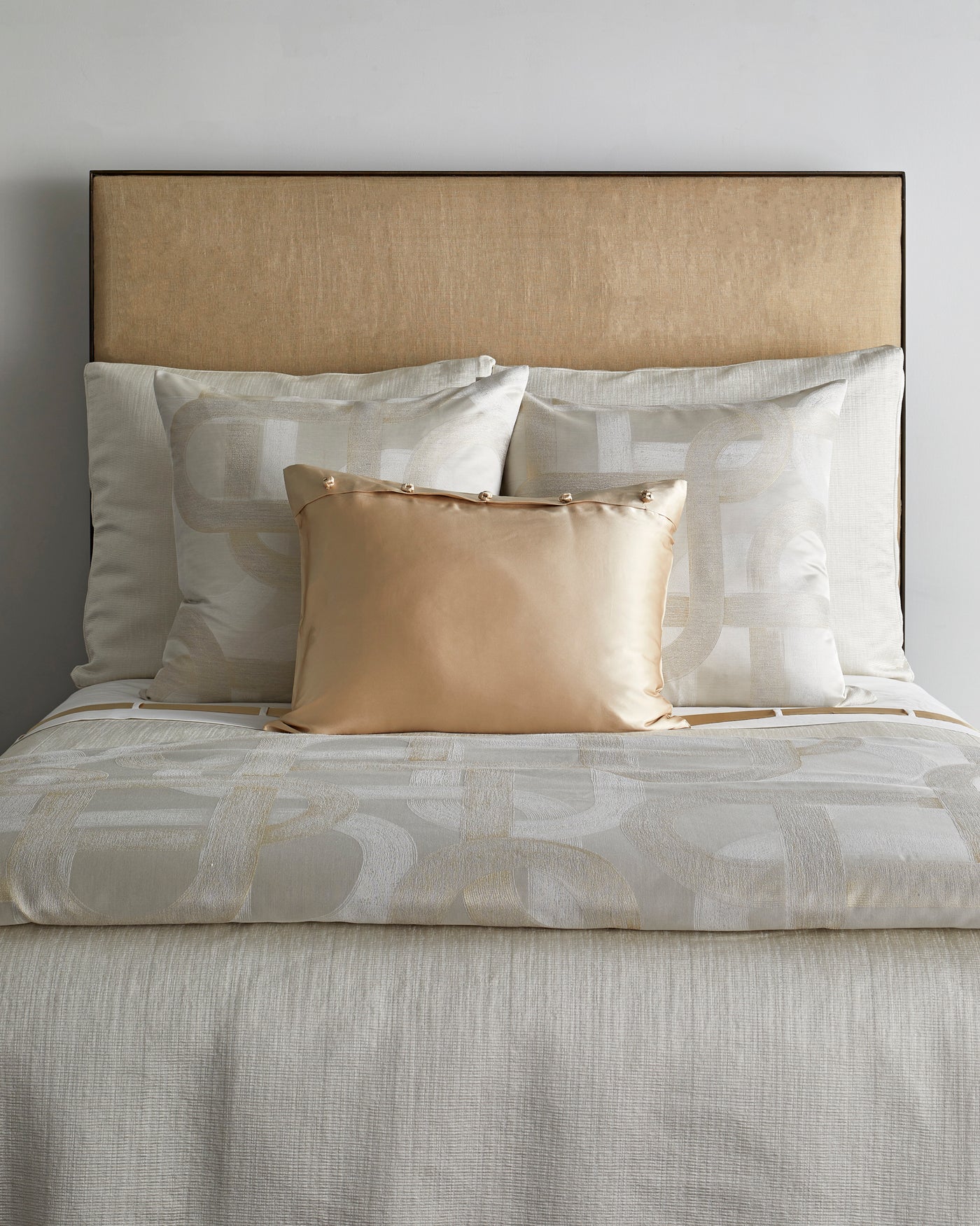Styled bed with ivory geometric jacquard duvet and champagne silk accent pillow.