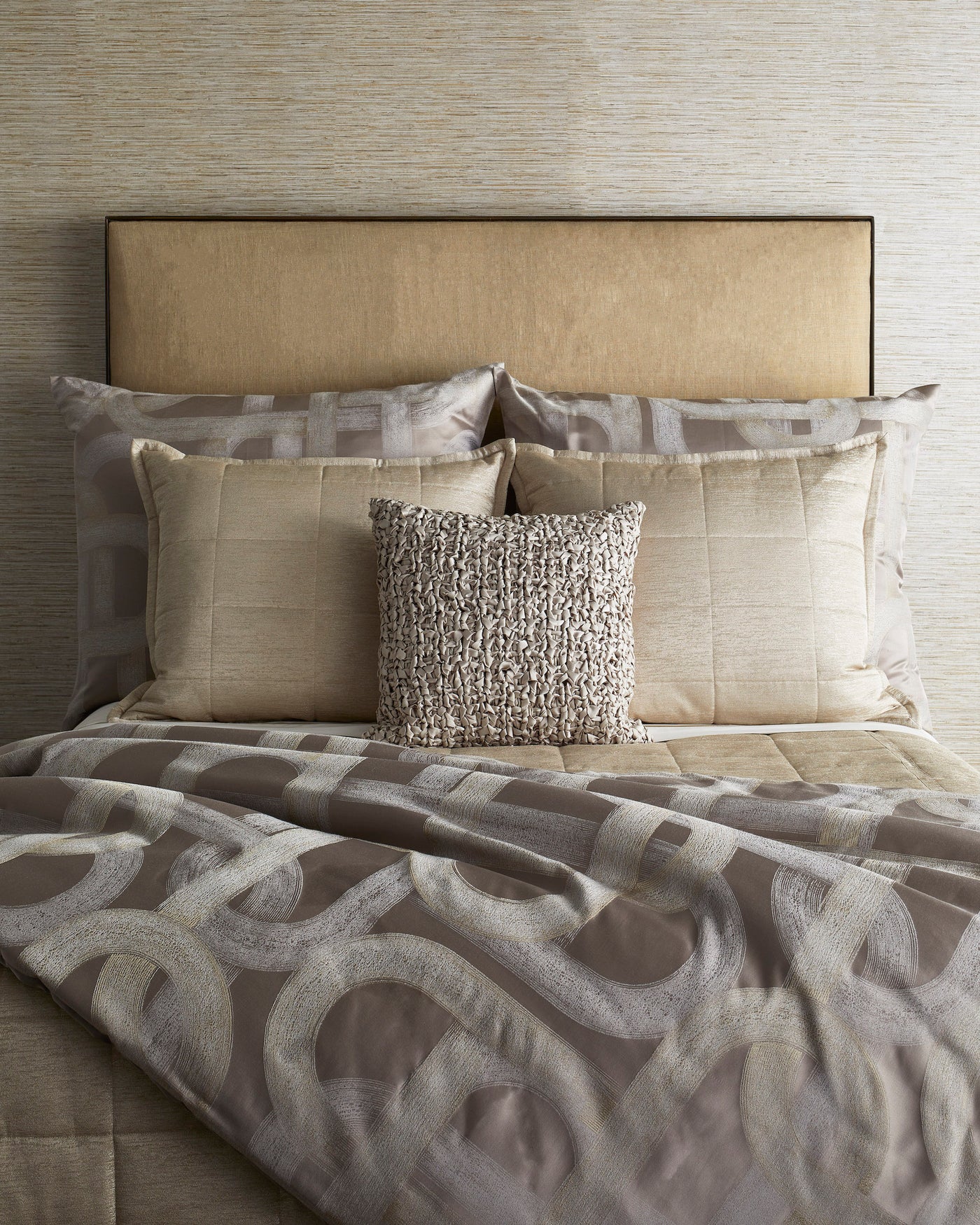 Taupe and ivory abstract loop pattern duvet styled on bed with layered neutral pillows.
