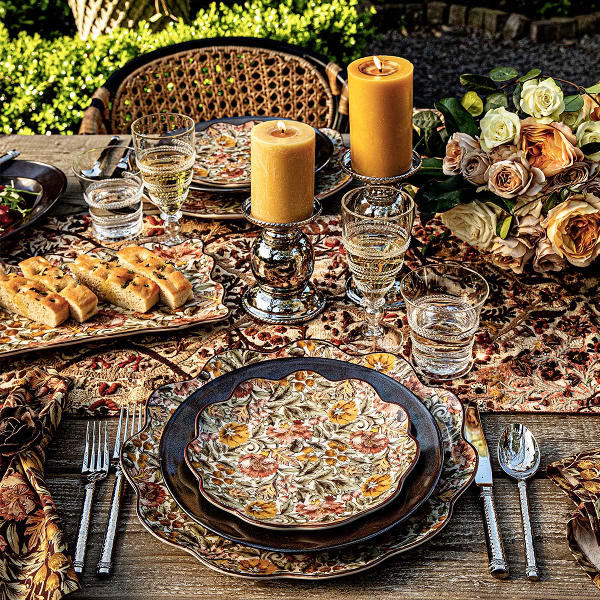 Juliska Willa salad plate on a dark charger at an outdoor table with candles and roses