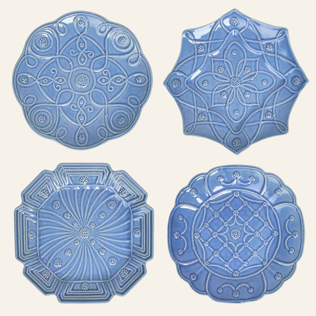Overhead view of four periwinkle embossed ceramic dessert plates, each with a distinct relief pattern.