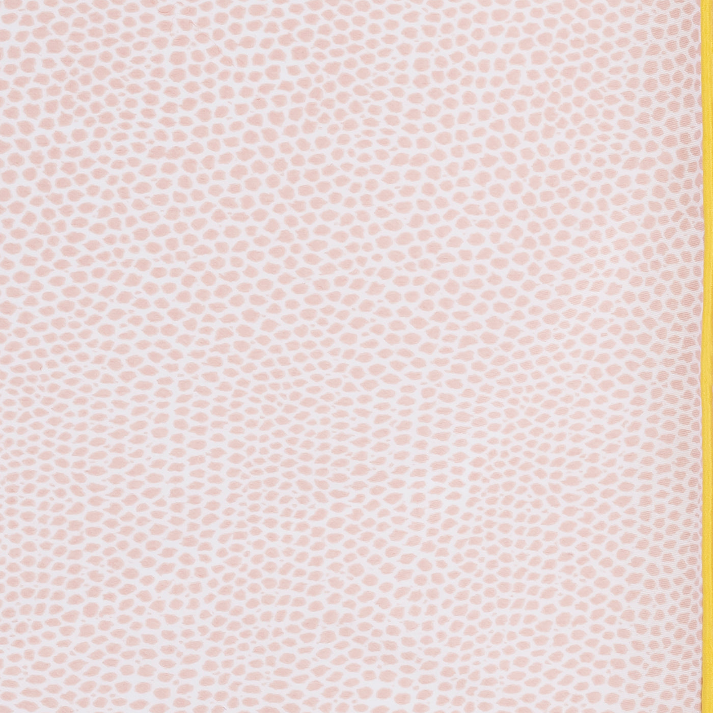 Close-up of blush dotted cotton fabric with a mustard yellow contrast edge trim.