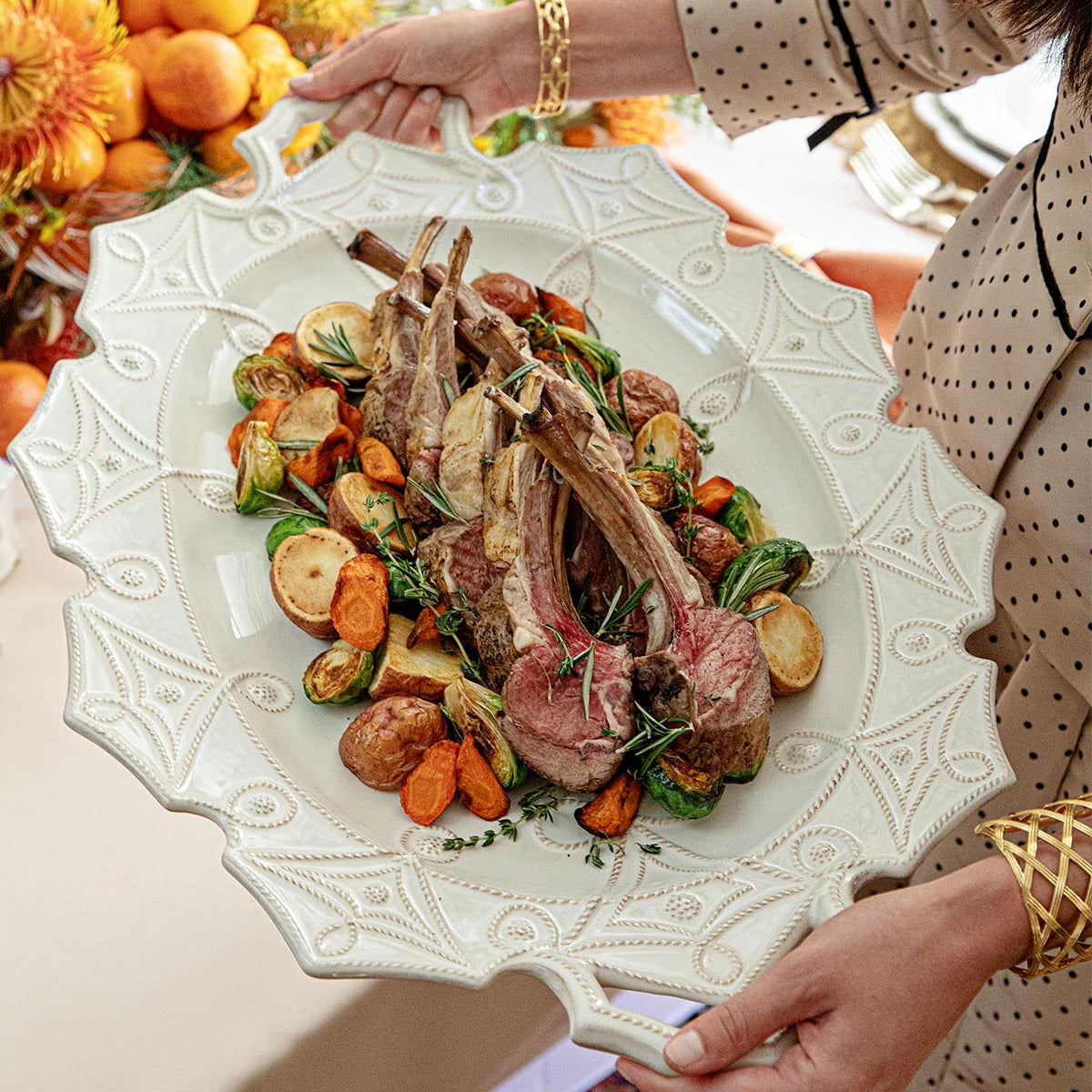 Juliska Jardins du Monde ivory embossed platter held with rack of lamb and roasted vegetables.