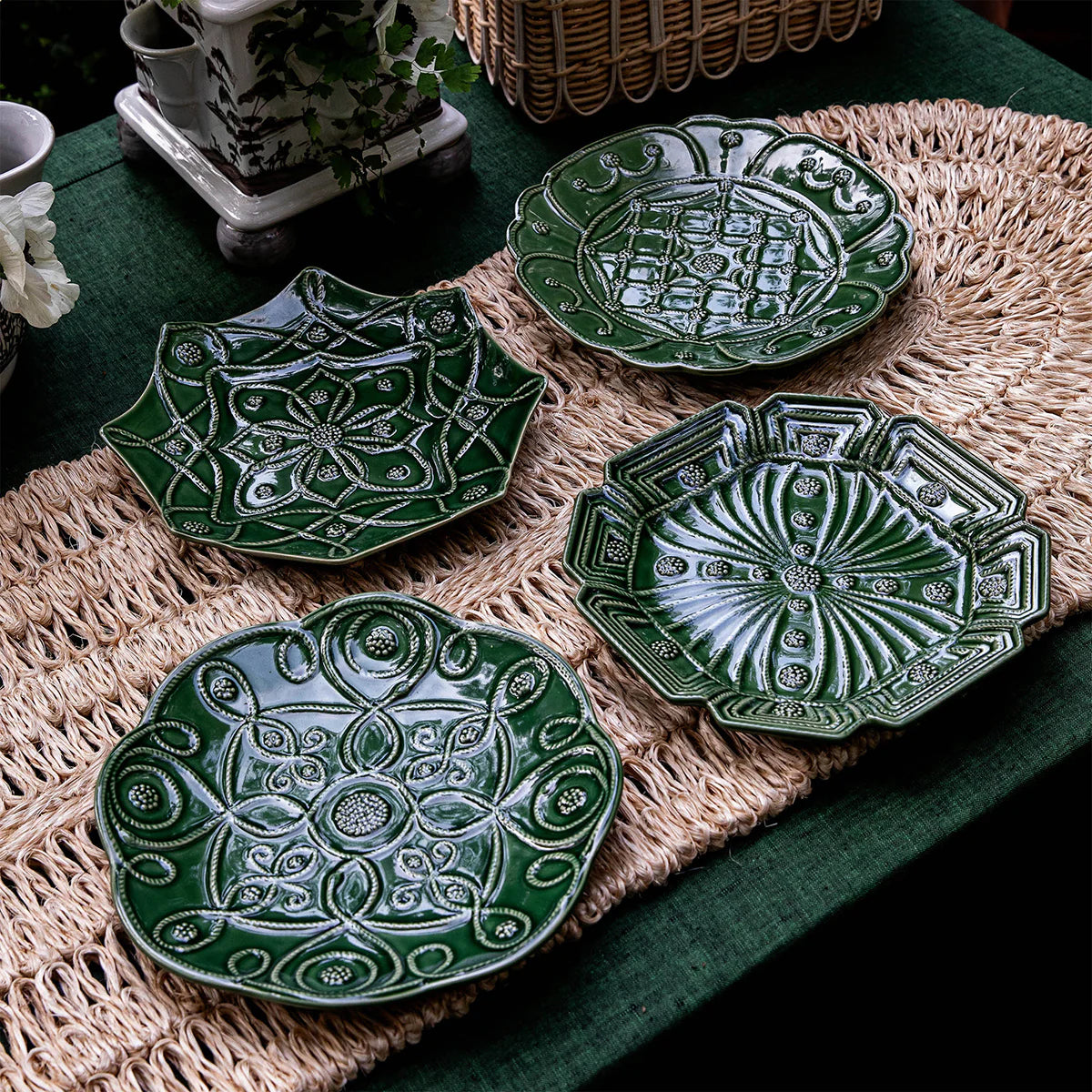 Close-up of four Juliska forest green embossed ceramic dessert plates on woven runner.