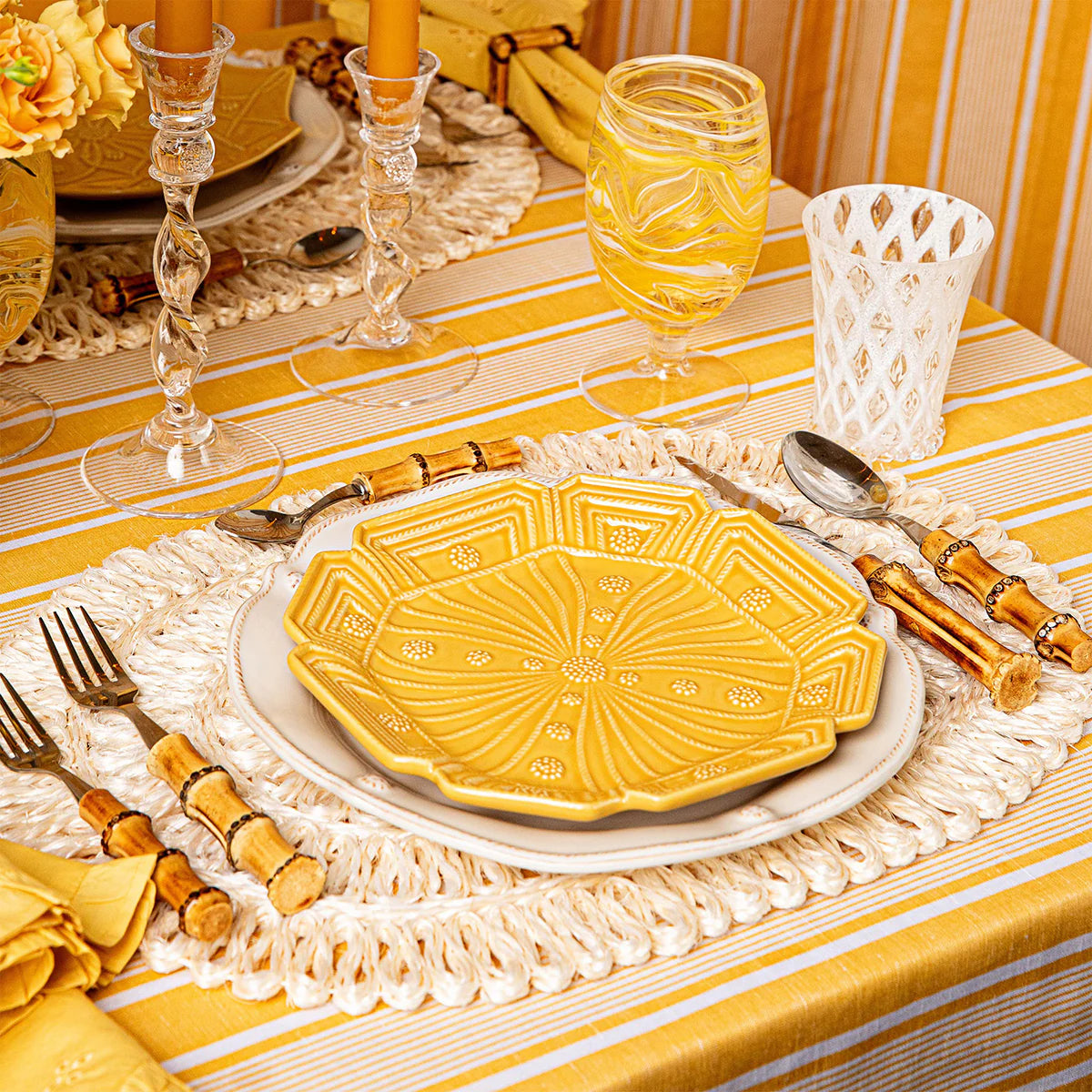 Juliska saffron embossed ceramic dessert plate on woven shell charger, yellow stripe linen.