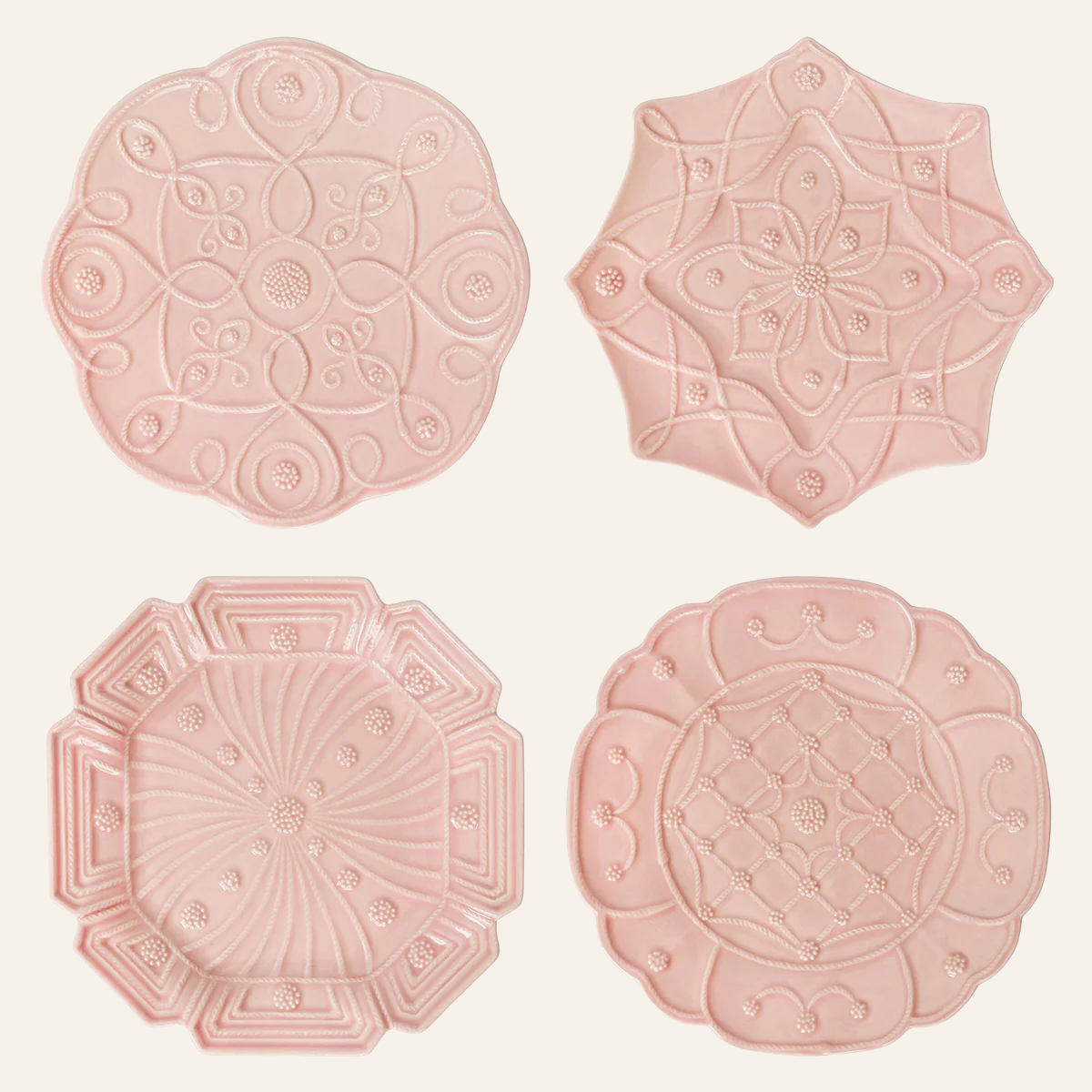 Four blush ceramic dessert plates with varied embossed botanical and geometric motifs.