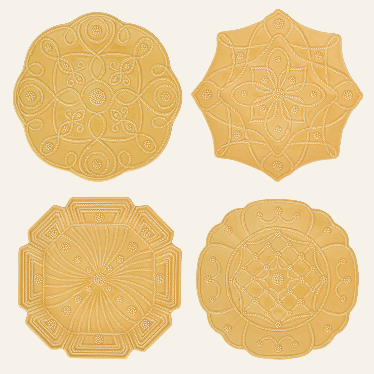 Four saffron Juliska Jardins Du Monde dessert plates showing varied embossed medallion patterns.