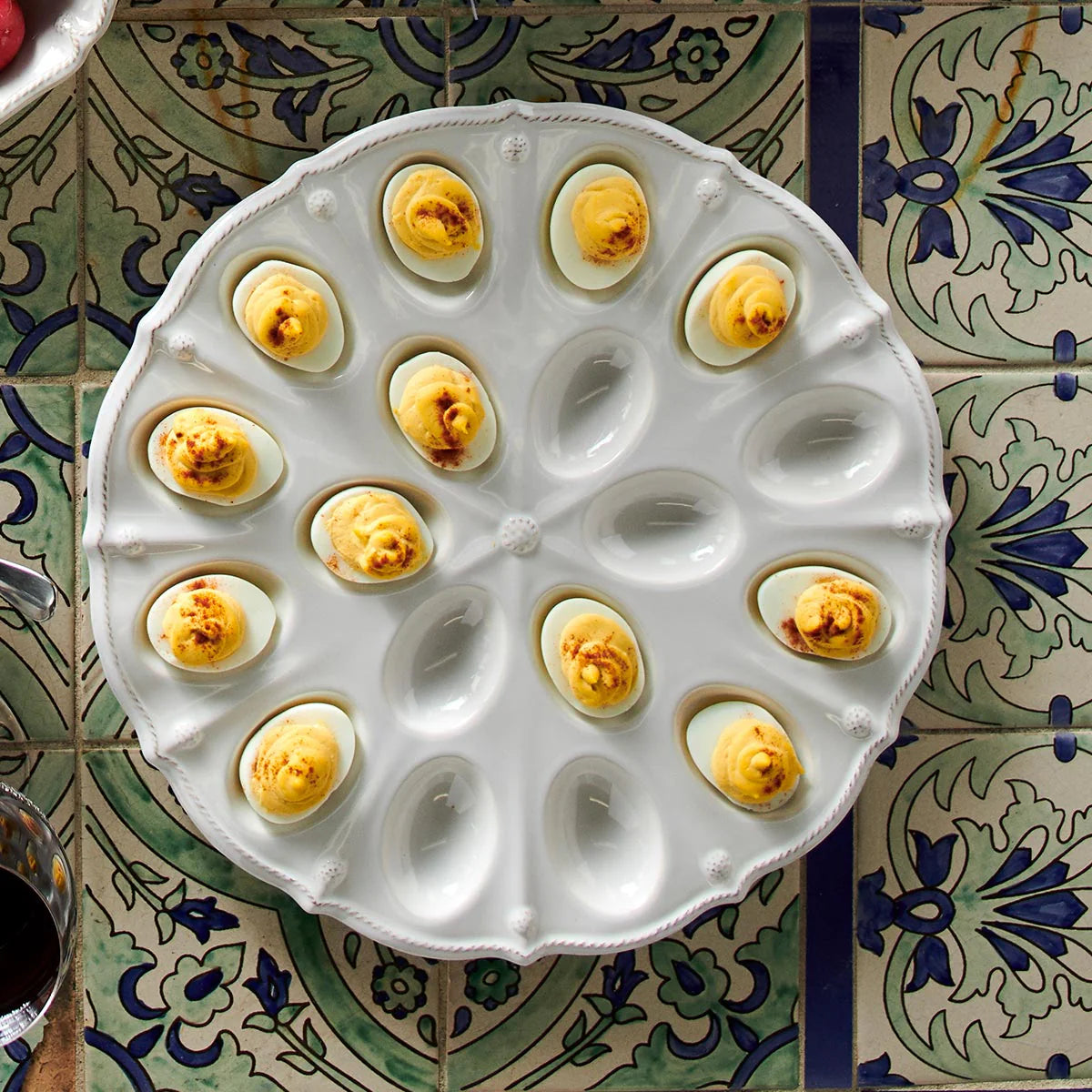 Overhead view of Juliska Berry & Thread white ceramic deviled egg platter styled with filled eggs on tile surface.