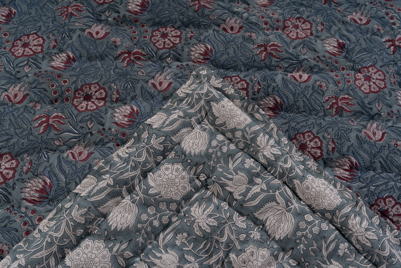 Close-up of quilted slate blue cotton with dusty rose and ivory botanical block print pattern.