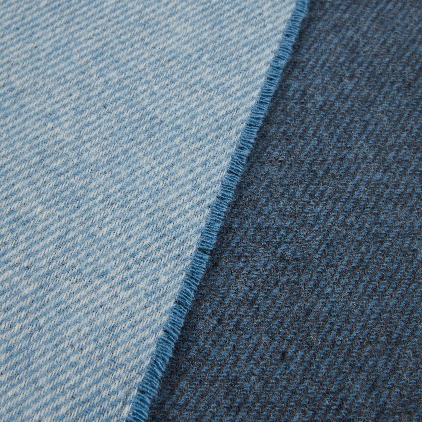 Close-up of Lanerossi Ascot throw showing light and dark blue reversible sides with fringed edge.