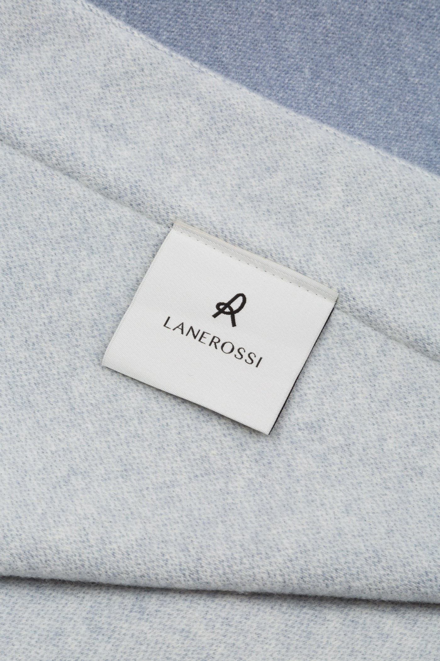 Close-up of Lanerossi Afrodite blanket label on pale blue wool fabric with contrast border.