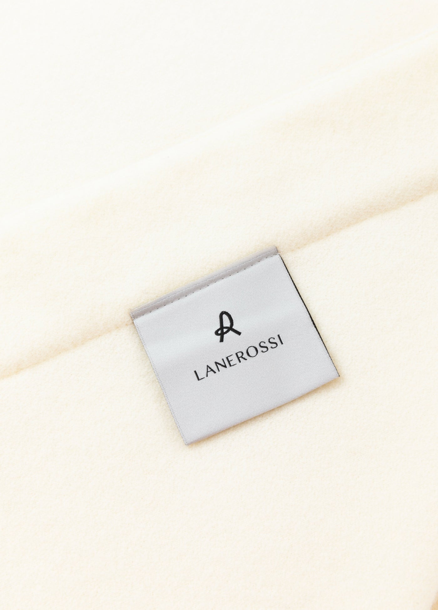 Close-up of Lanerossi label on ivory wool blanket corner.