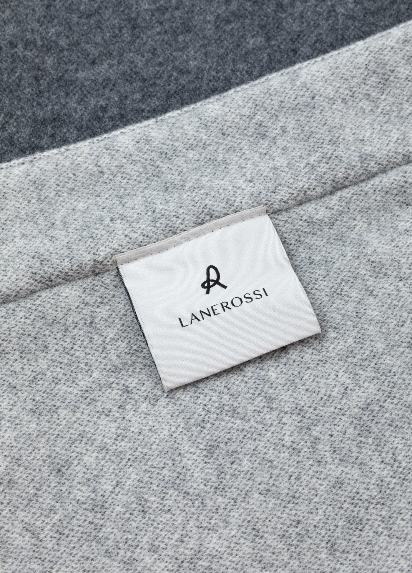 Close-up of Lanerossi woven label on grey melange wool blanket corner.