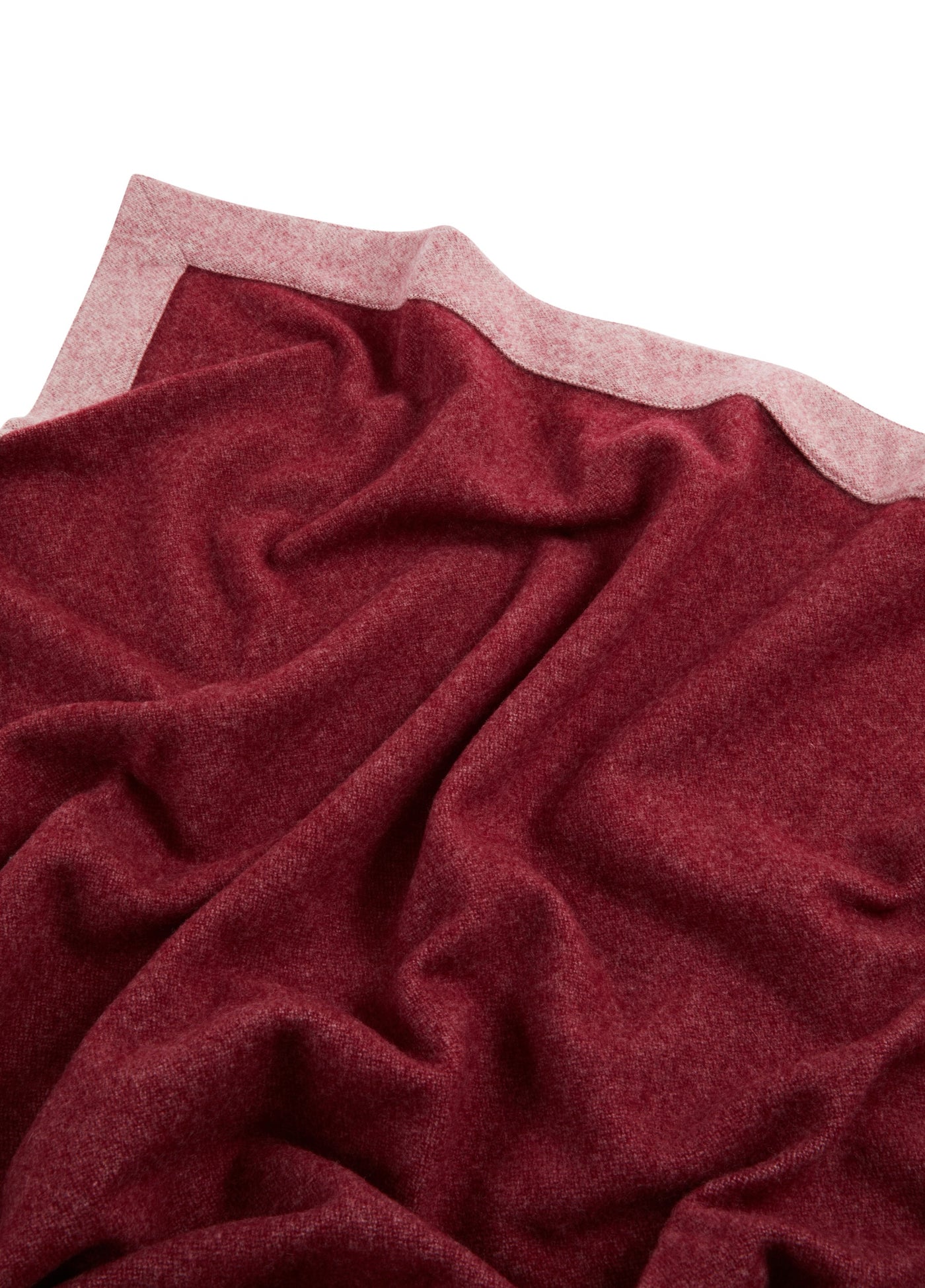 Crimson wool blanket draped to reveal blush reverse side and soft knit texture.