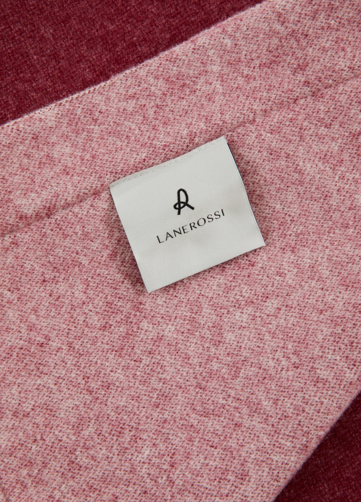 Close-up of Lanerossi label on rose and burgundy wool blanket border detail.