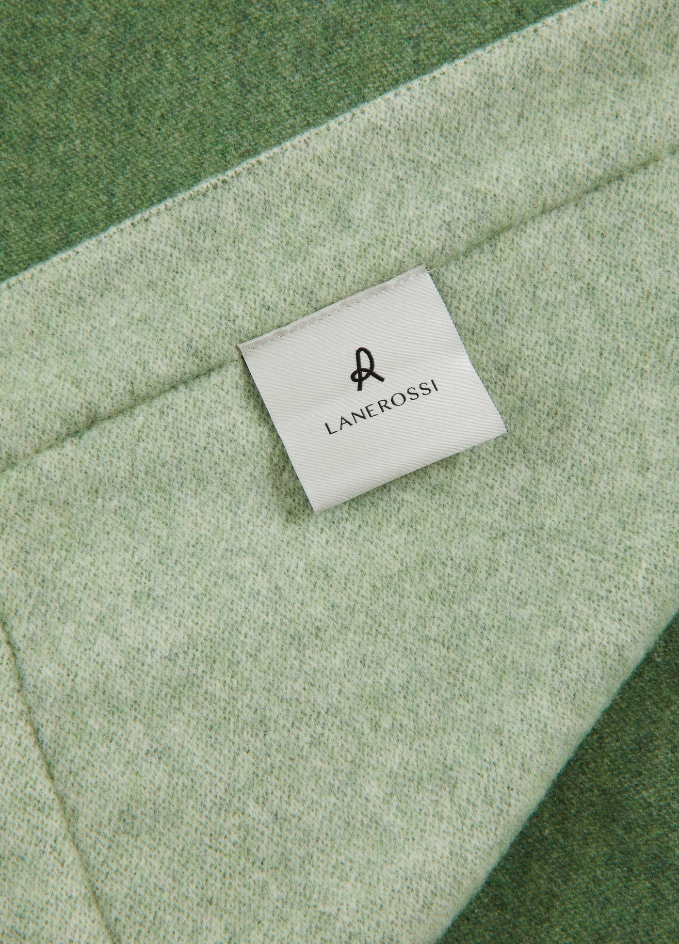 Close-up of Lanerossi Afrodite blanket label on sage green wool fabric with darker border.