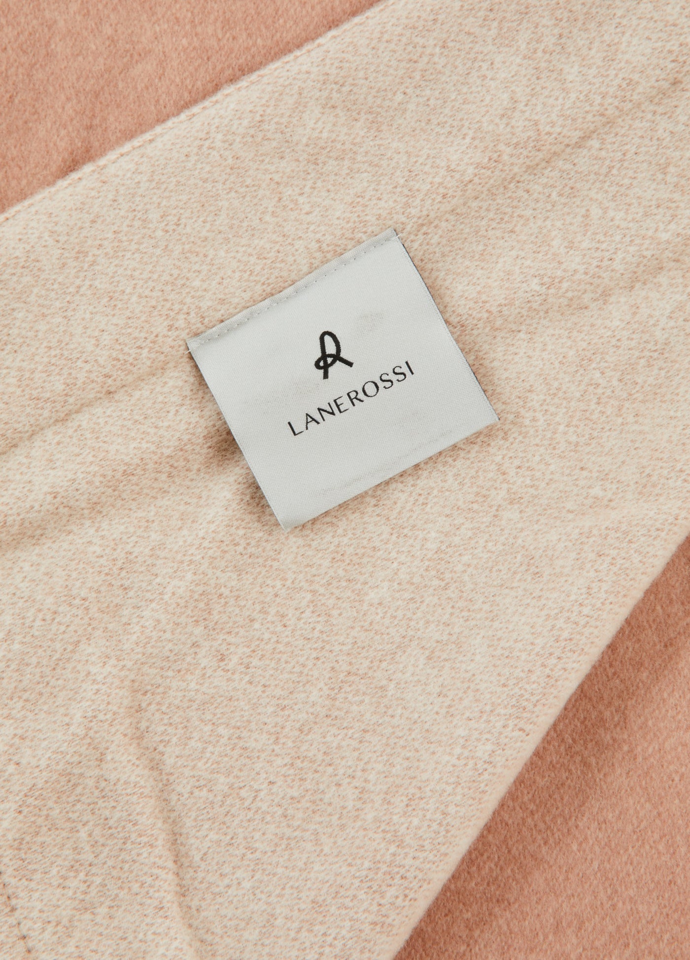 Close-up of Lanerossi woven label on draped blush and ivory wool blanket.