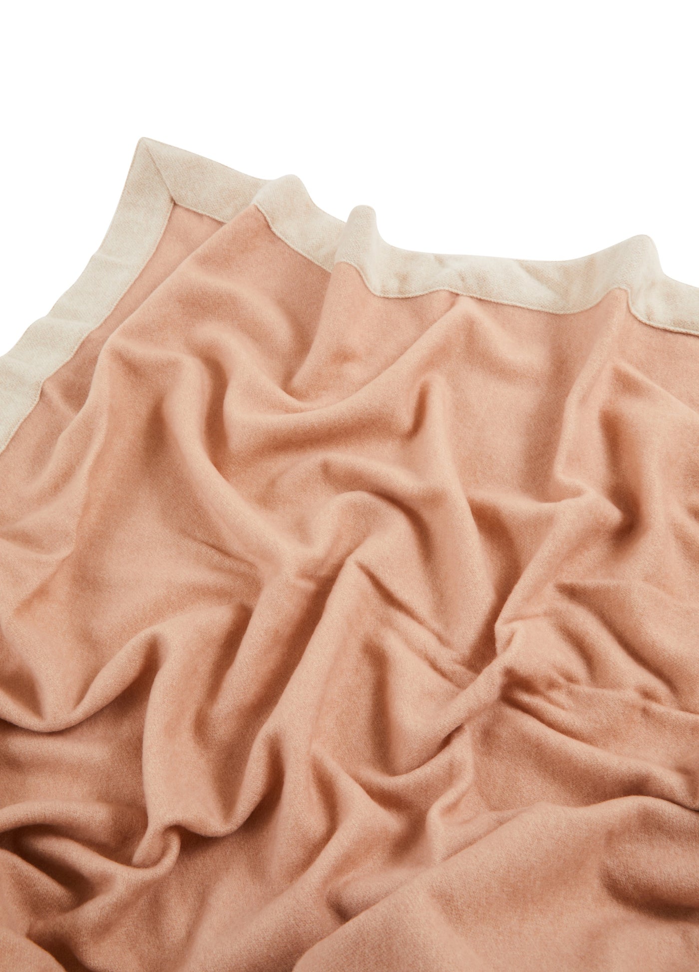 Draped blush wool blanket with ivory border trim, showing soft folds and texture.