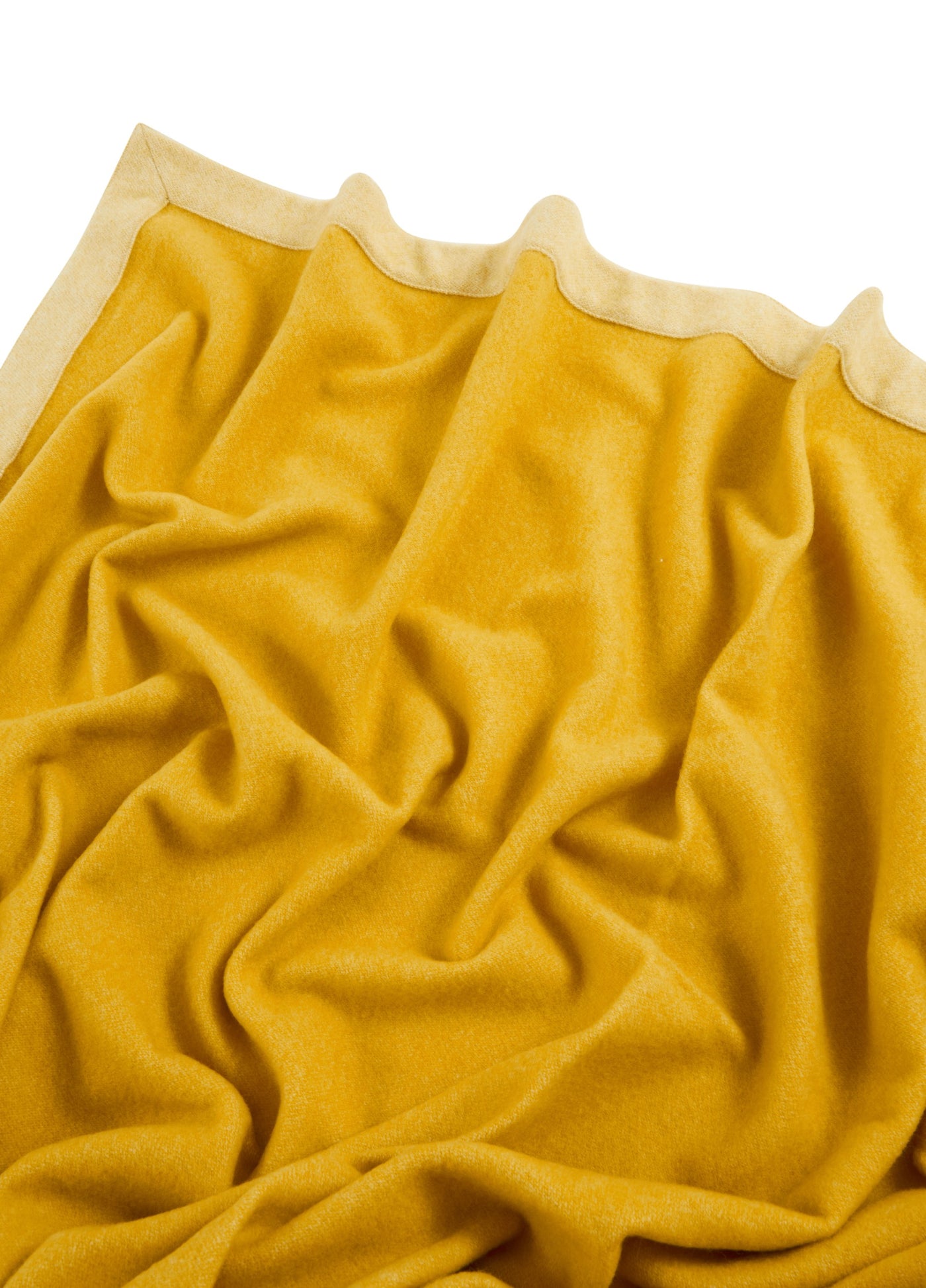 Close-up of saffron wool blanket with scalloped champagne border edge.